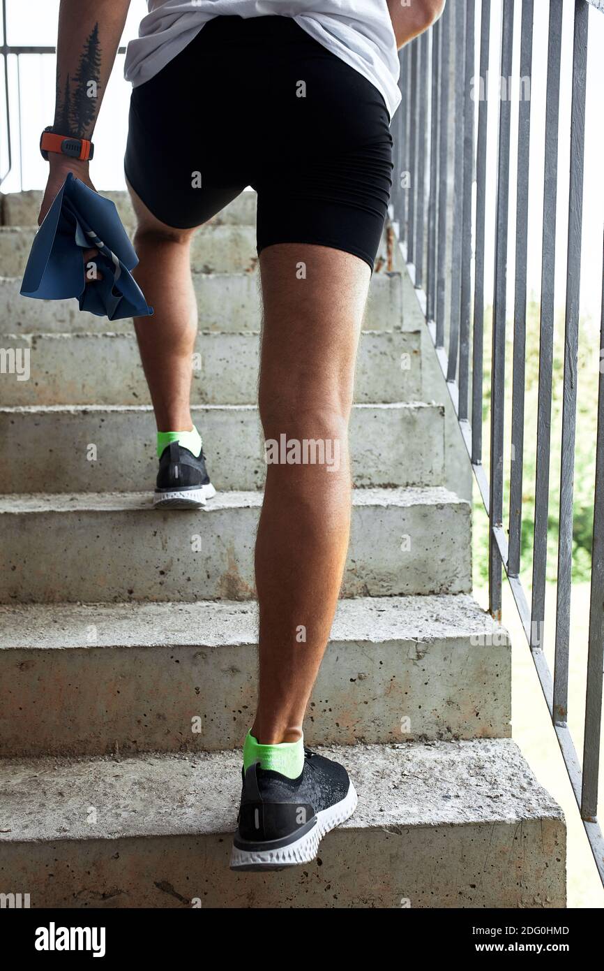 Atleta maschile concentrato che corre sulle scale per rendere l'allenamento più intensivo. Sportivo bello giovane uomo allenarsi da solo all'aperto. Punto di allenamento per scale Foto Stock