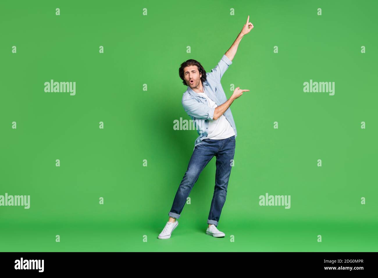 Foto a lunghezza intera di giovane uomo storto sollevare le braccia  indicano dita danza indossare denim camicia jeans sneakers isolato colore  verde sfondo Foto stock - Alamy