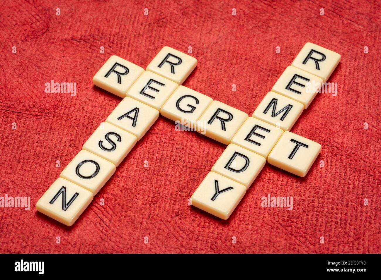 Rimpianto, ragione, rimedio crossword in avorio lettere tessere contro textured handmade carta, business e concetto di gestione di crisi Foto Stock