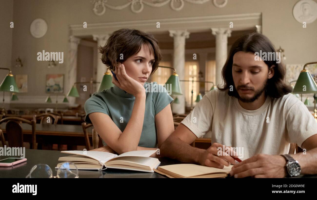 Giovani studenti attraenti che fanno i compiti insieme nella biblioteca del college. Studenti che studiano all'università Foto Stock