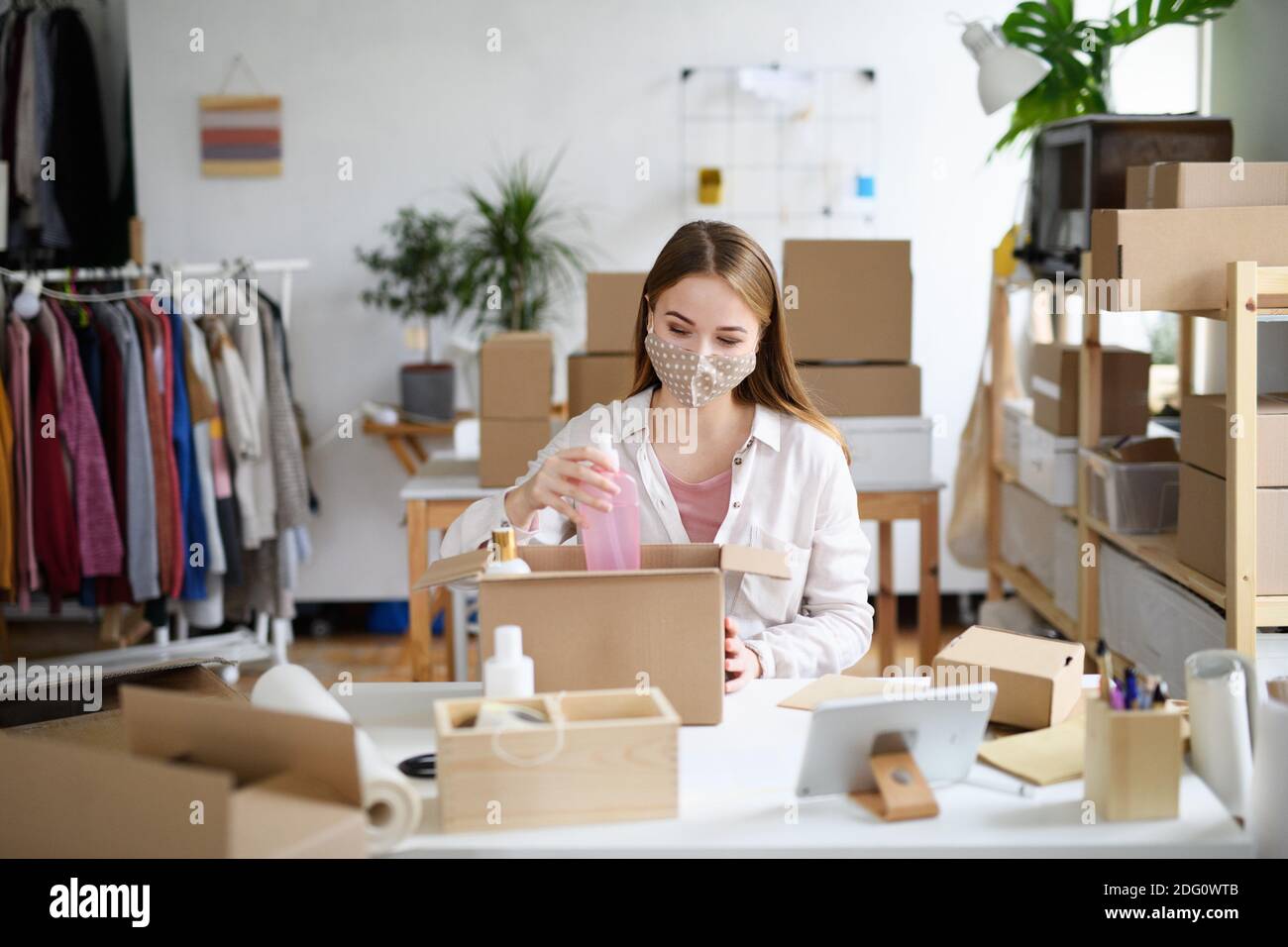 Giovane donna dropshipper che lavora a casa, elaborando gli ordini. Concetto di coronavirus. Foto Stock