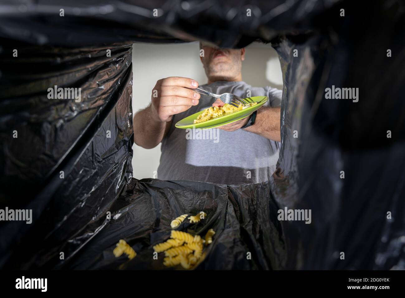 l'uomo getta la pasta nel bidone. consumo eccessivo. vista dal bidone dei rifiuti Foto Stock