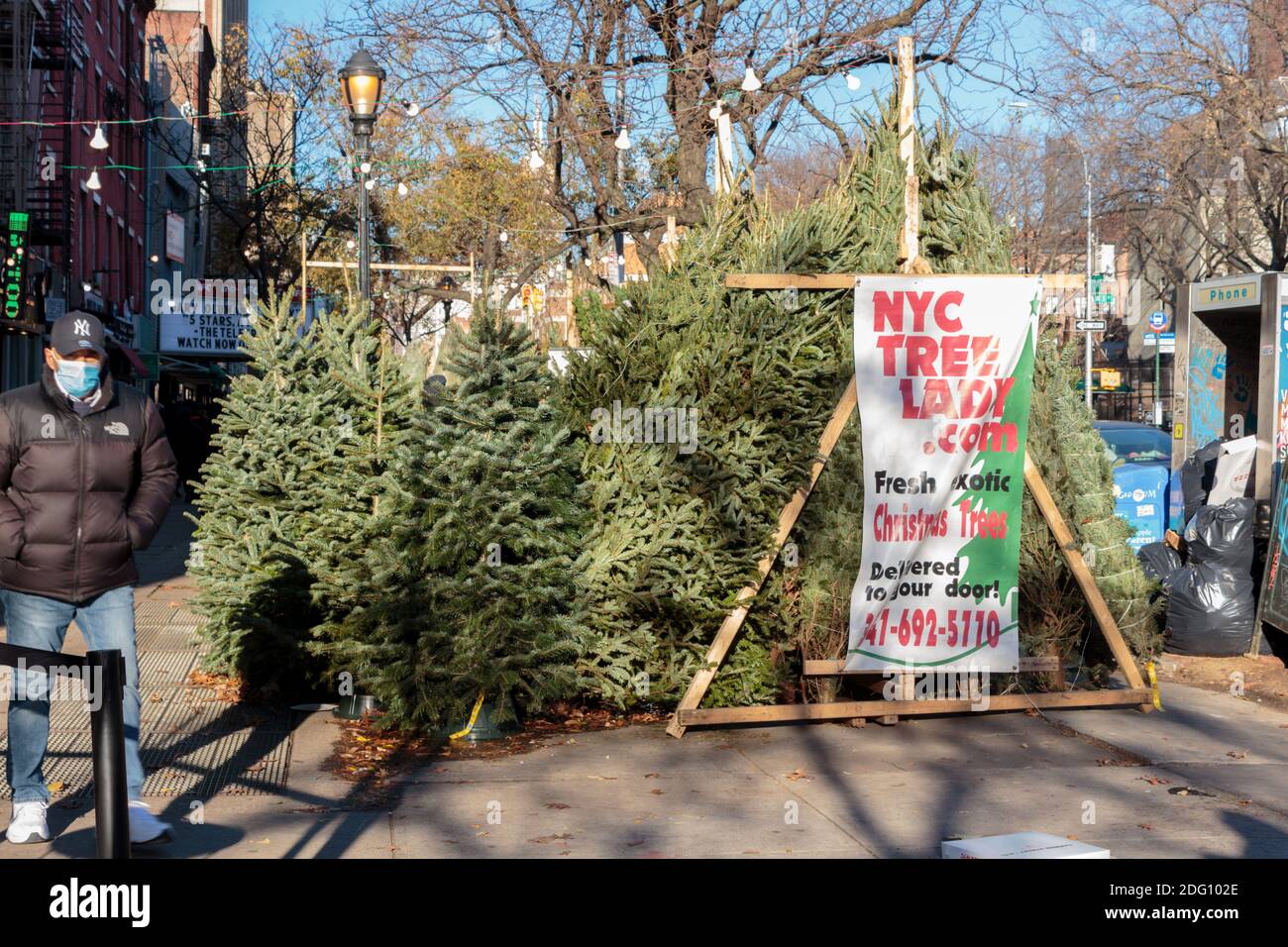 sidewalk vendita albero di natale nel villaggio di greenwich a new york città mentre un uomo cammina in una maschera facciale durante il coronavirus o covid-19 pandemia Foto Stock