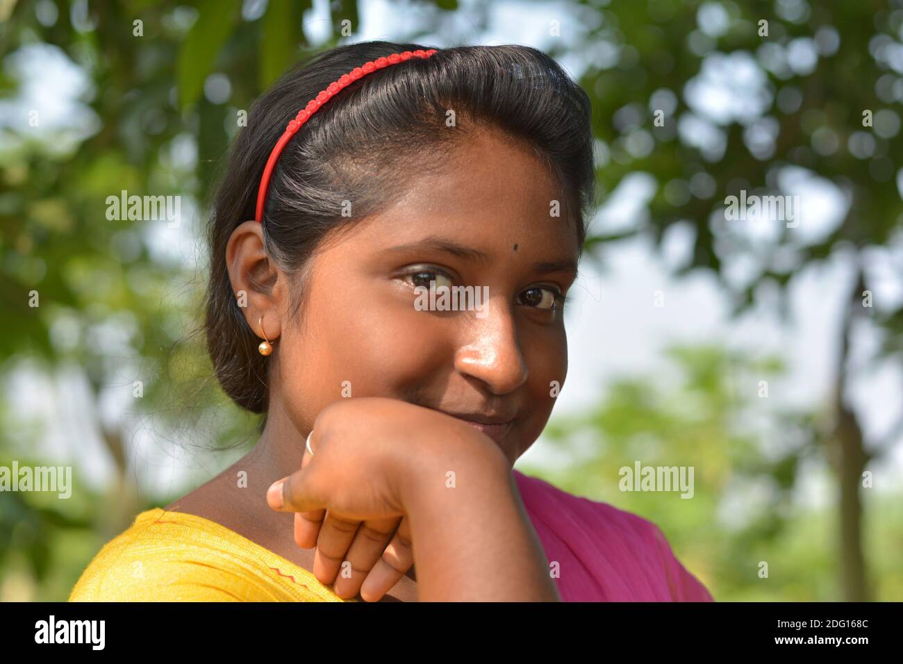 Primo piano di una ragazza indiana bengalese che indossa giallo salwar colore e rosa dhupatta con bindi sulla fronte, messa a fuoco selettiva Foto Stock