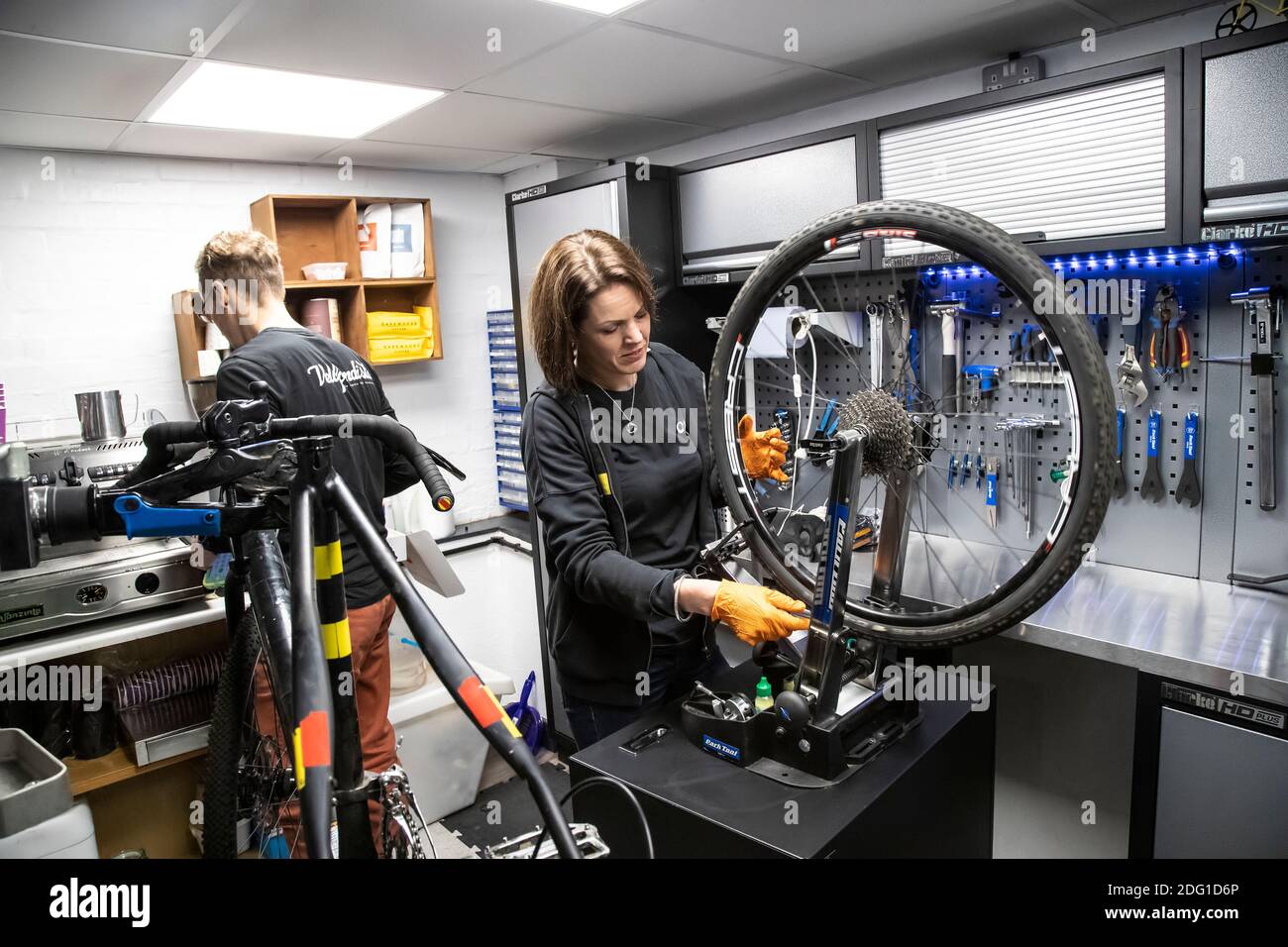Un tecnico di bici Cytech completamente qualificato che controlla l'allineamento di una ruota posteriore della bicicletta in una riparazione professionale dedicata e. officina di manutenzione Foto Stock
