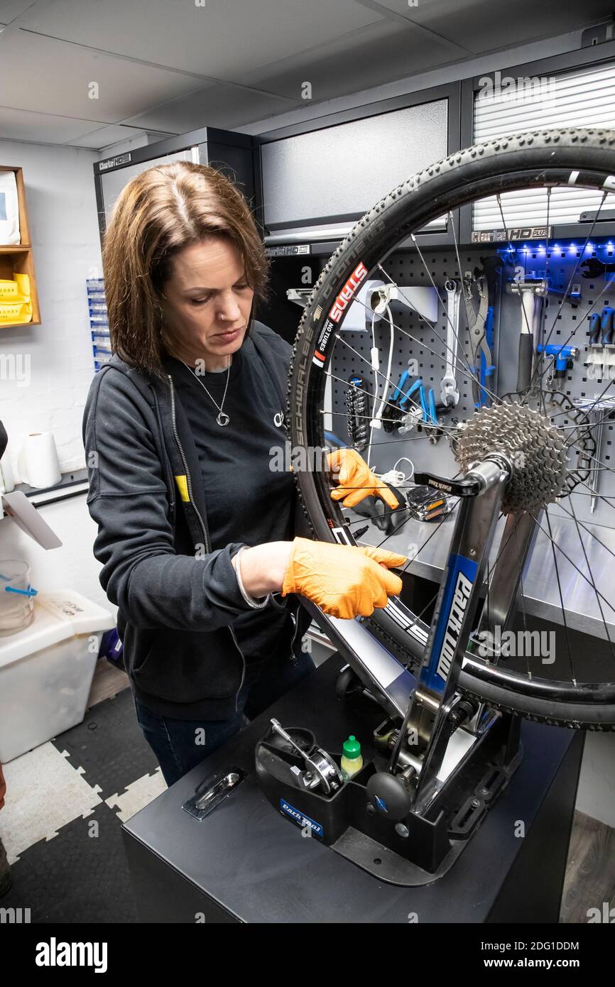 Un tecnico di bici Cytech completamente qualificato che controlla l'allineamento di una ruota posteriore della bicicletta in una riparazione professionale dedicata e. officina di manutenzione Foto Stock