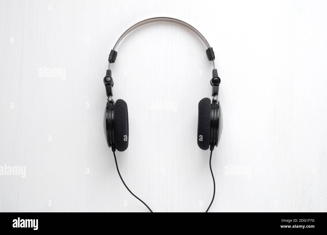 Cuffie cablate per ascoltare musica su sfondo bianco di legno. Concetto per  illustrare l'ascolto della musica Foto stock - Alamy