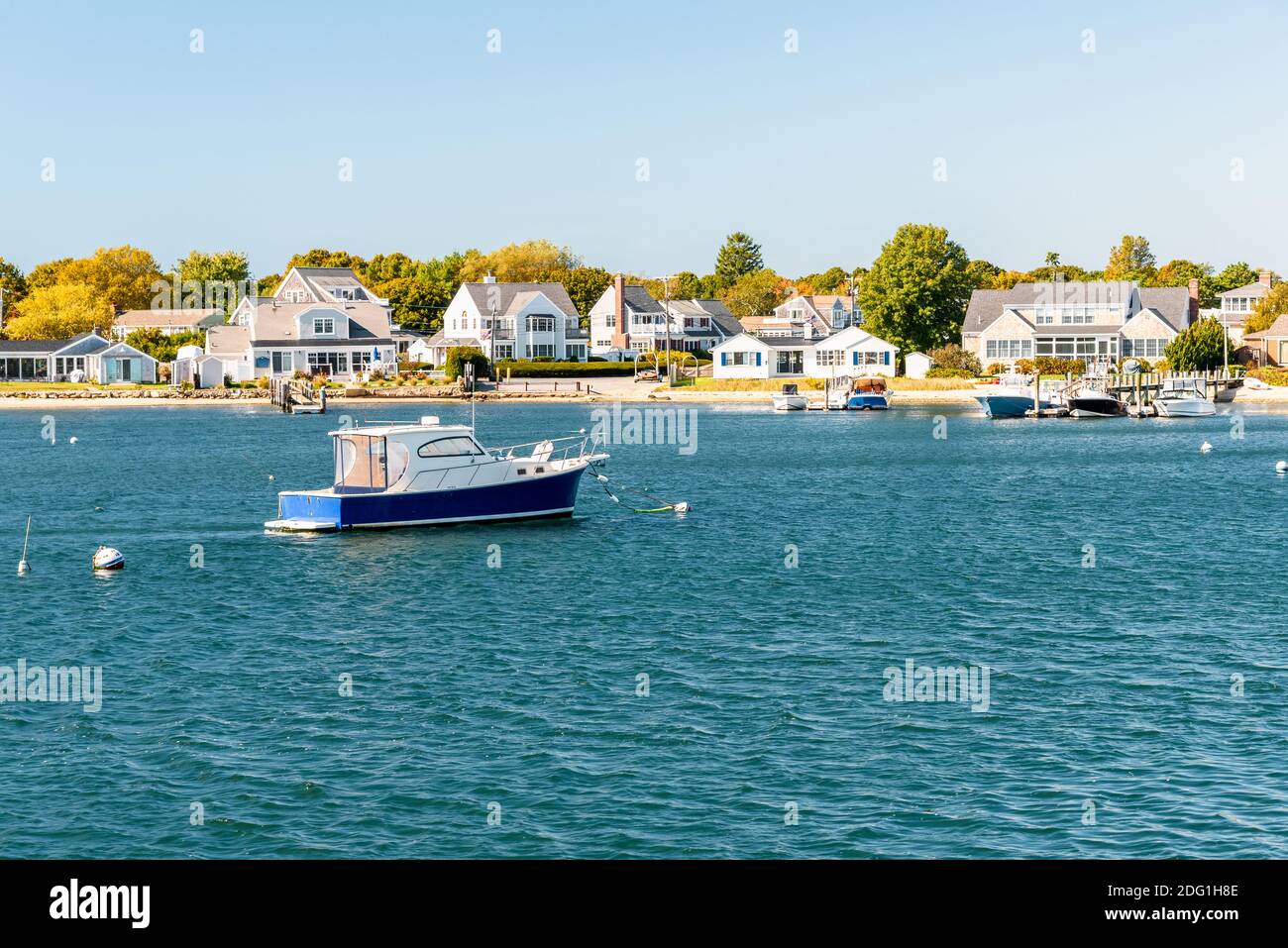 Barca vuota ormeggiata al largo di una costa sabbiosa fiancheggiata da edifici residenziali con jetties in legno privato. Hyannis, Capo Cod, ma, Stati Uniti. Foto Stock