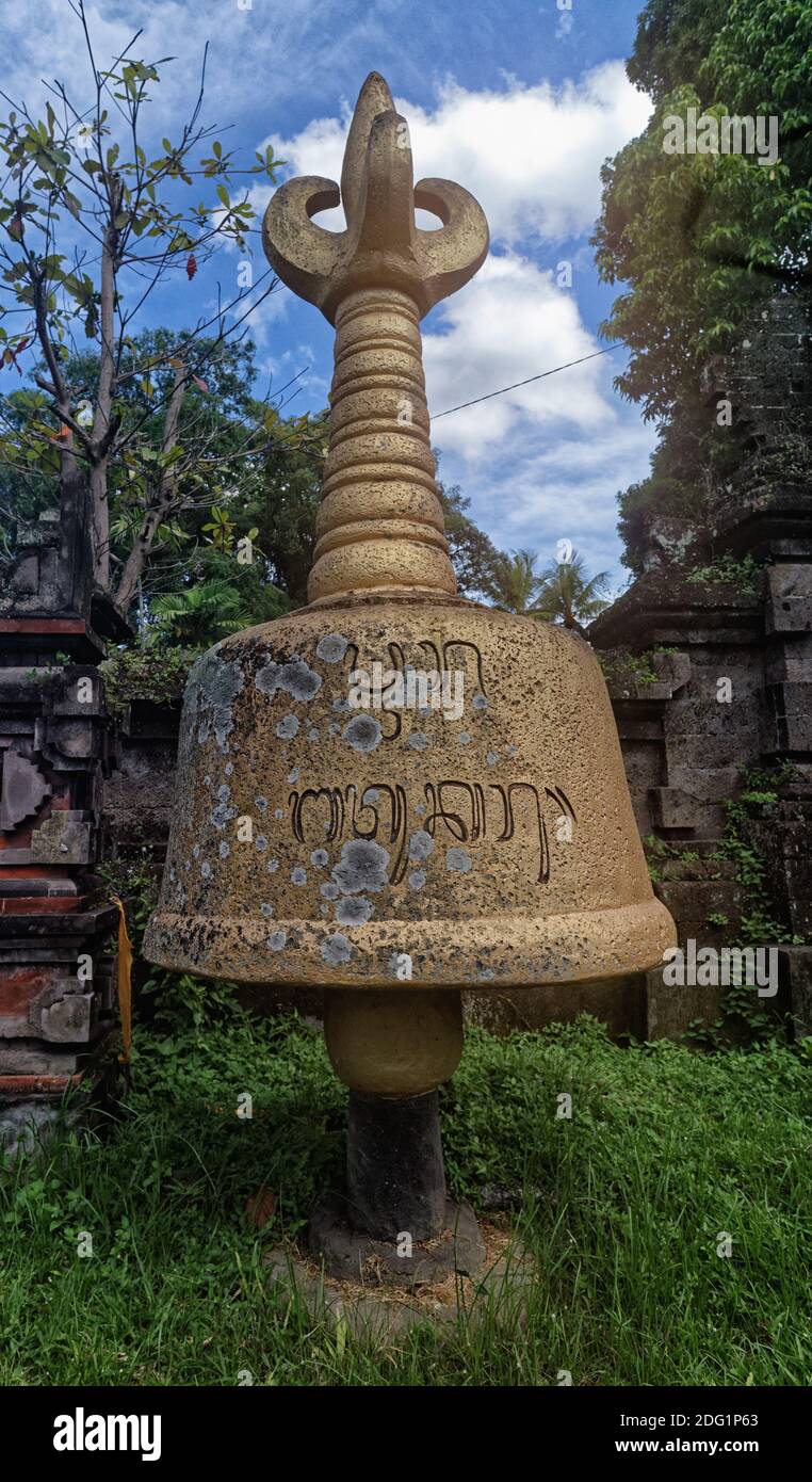 Pietra carta campana puja con dorje in cima, in una parete stradale, Bali, Indonesia Foto Stock