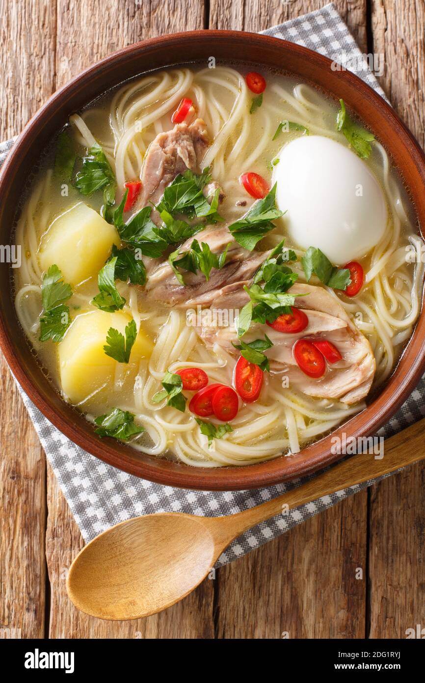 Peruviana caldo de gallina zuppa di noodle di pollo primo piano in un piatto sul tavolo. Vista dall'alto verticale Foto Stock