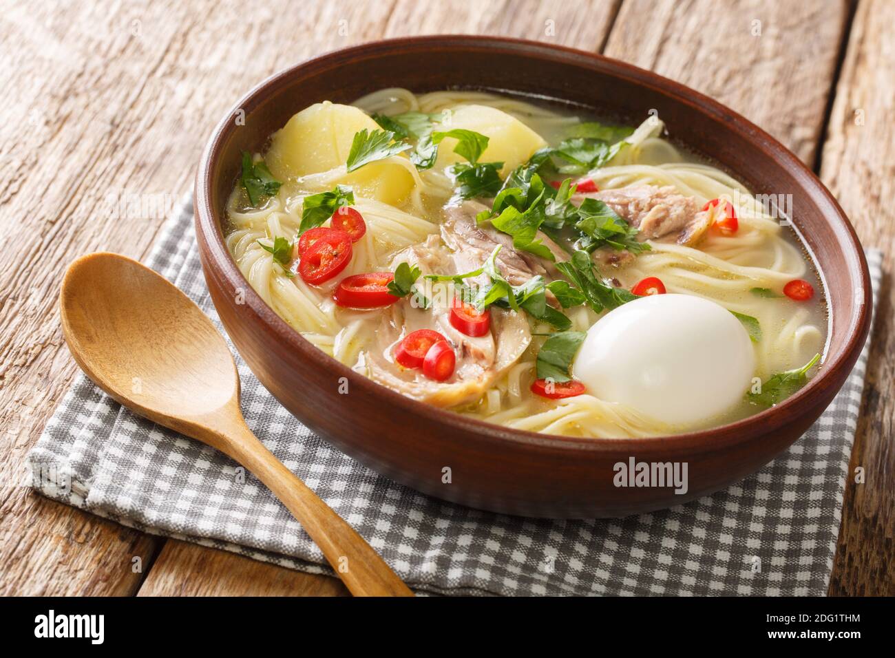 Cibo peruviano Caldo de Gallina zuppa di noodle di pollo con uova sode ed erbe primo piano in un piatto sul tavolo. Orizzontale Foto Stock