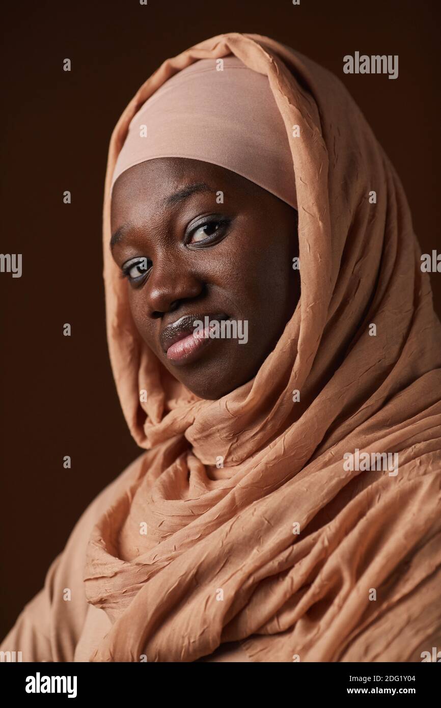 Ritratto verticale di una donna etnia afroamericana che indossa un velo e guarda in camera mentre si posa in studio Foto Stock