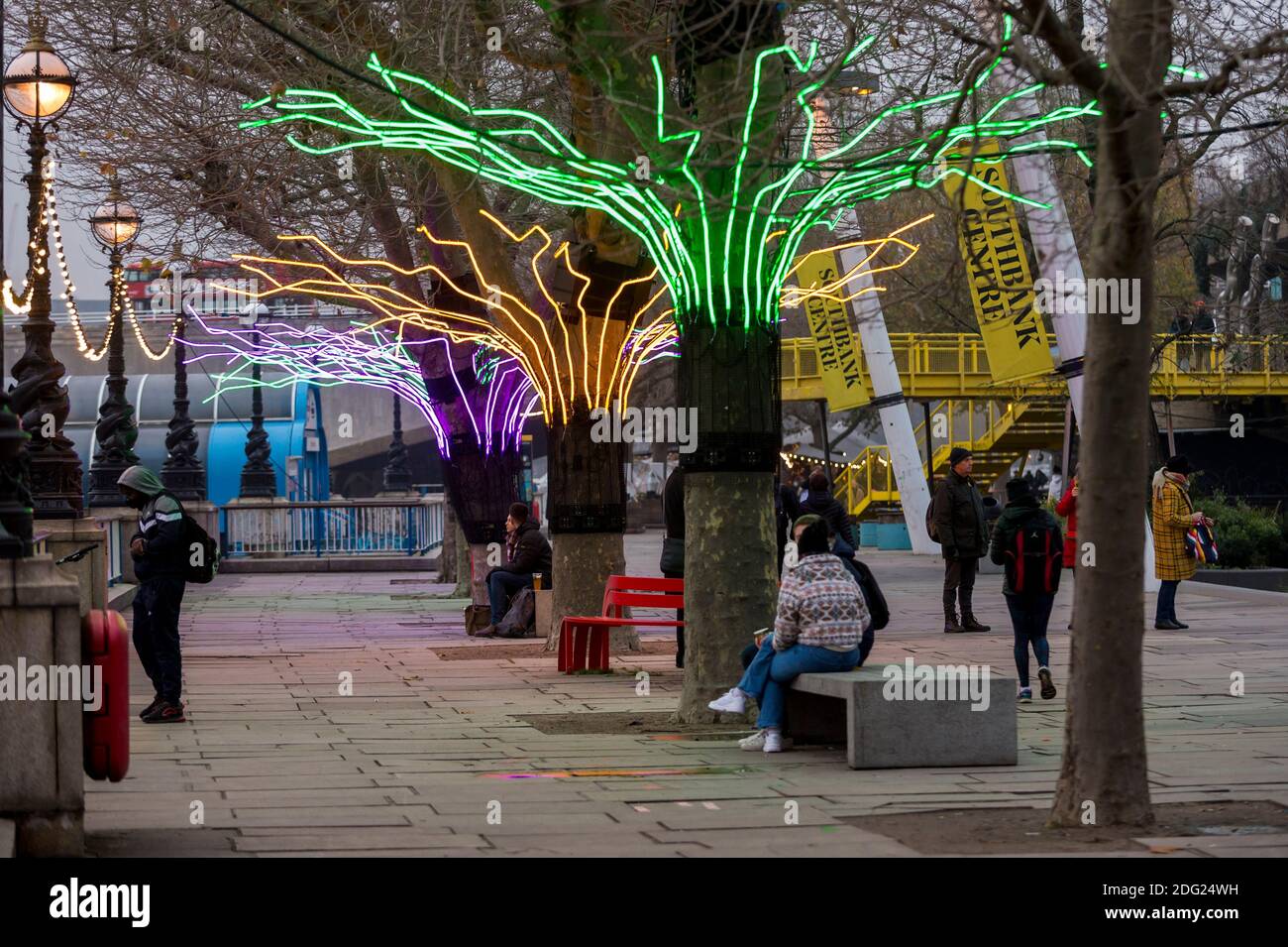 Londra, Regno Unito. 7 dicembre 2020. I membri del pass pubblico accanto a 'Lumen' di David Ogle, alberi illuminati con riflessi al neon. Anteprima di "Winter Light" presentata da Southbank Centre. Oltre 15 opere d'arte e nuove commissioni illuminate da una serie di artisti internazionali sono in mostra intorno agli edifici del sito e al Riverside Walk fino alla fine di febbraio 2021. Credit: Stephen Chung / Alamy Live News Foto Stock