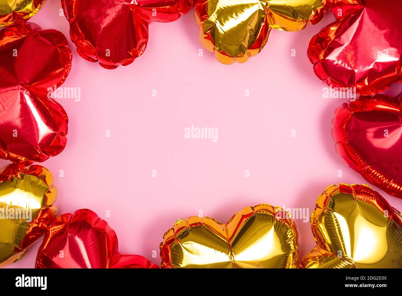 Cornice per testo con cuori rossi e dorati palloncini in foglio vista superiore su sfondo rosa San Valentino. CopySpace Foto Stock