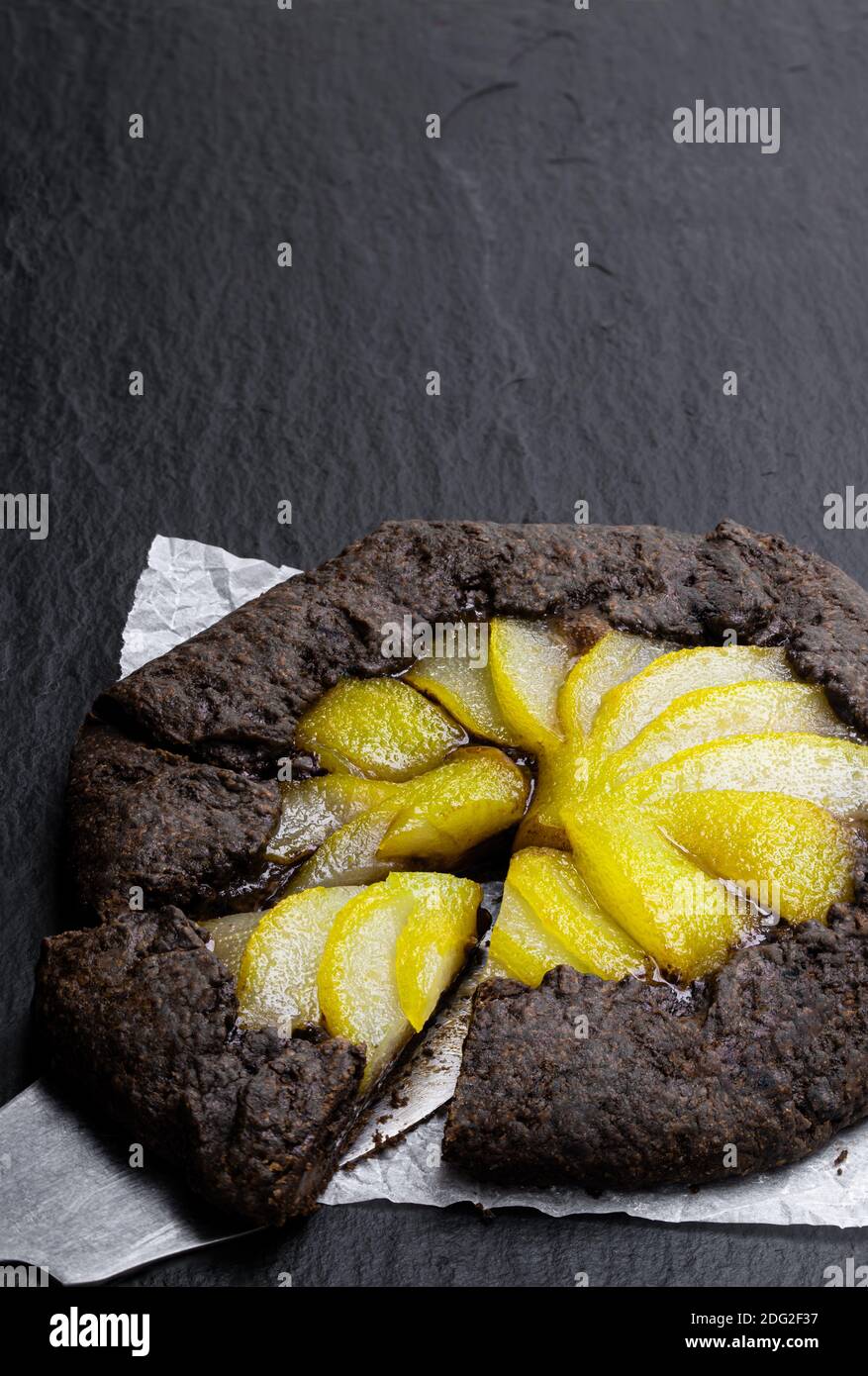 Crostata di cioccolato con pera in camicia su sfondo di pietra nera Foto Stock
