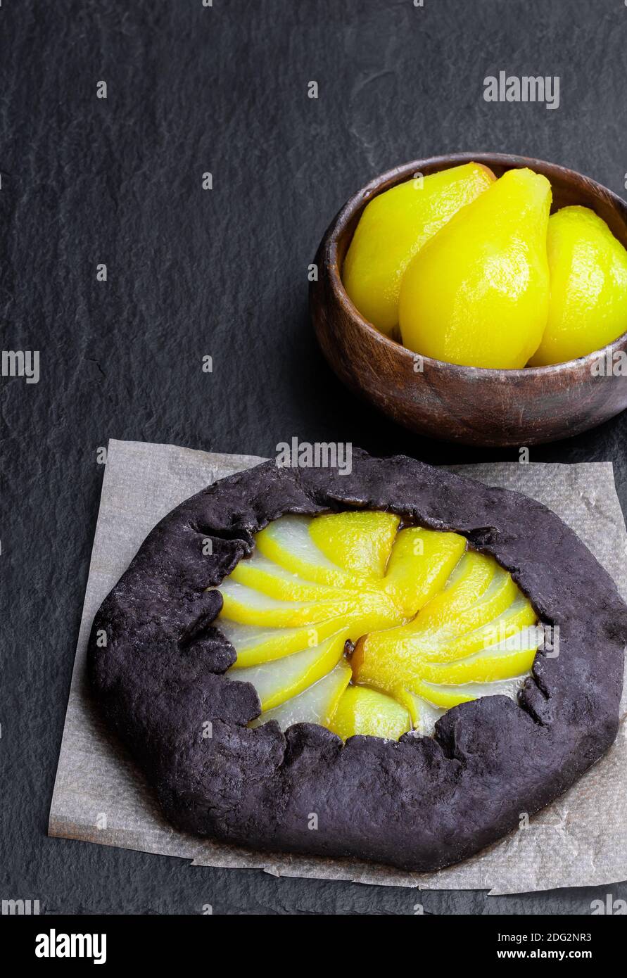 Crostata di cioccolato con pera in camicia su sfondo di pietra nera Foto Stock