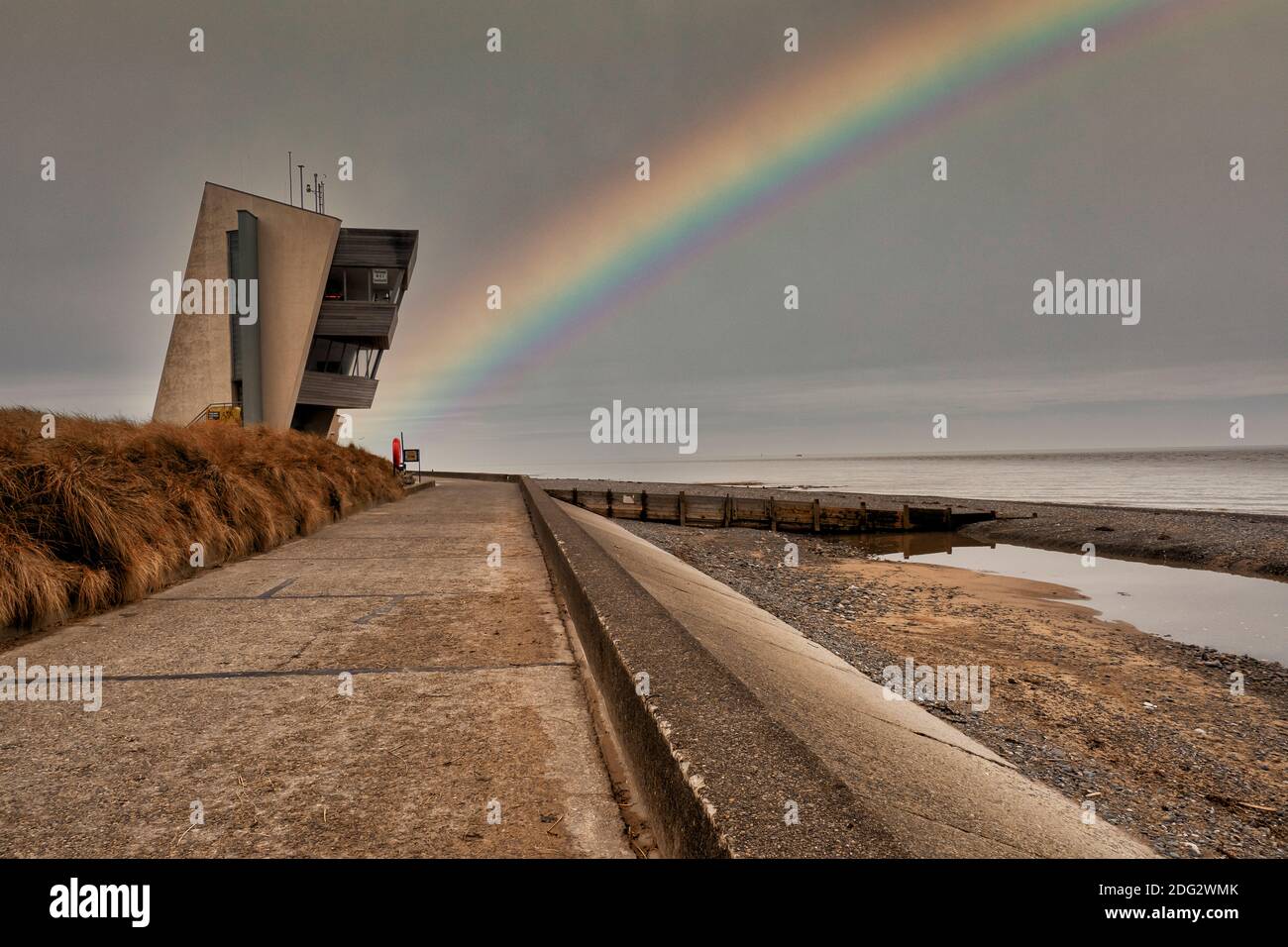 Rainbow at Rossall Beach, Fleetwood, Lancashire, Regno Unito. L'edificio a quattro piani sul lungomare esterno di Rossall Point e' la Torre dell'Orologio costiero di Rossall. Foto Stock