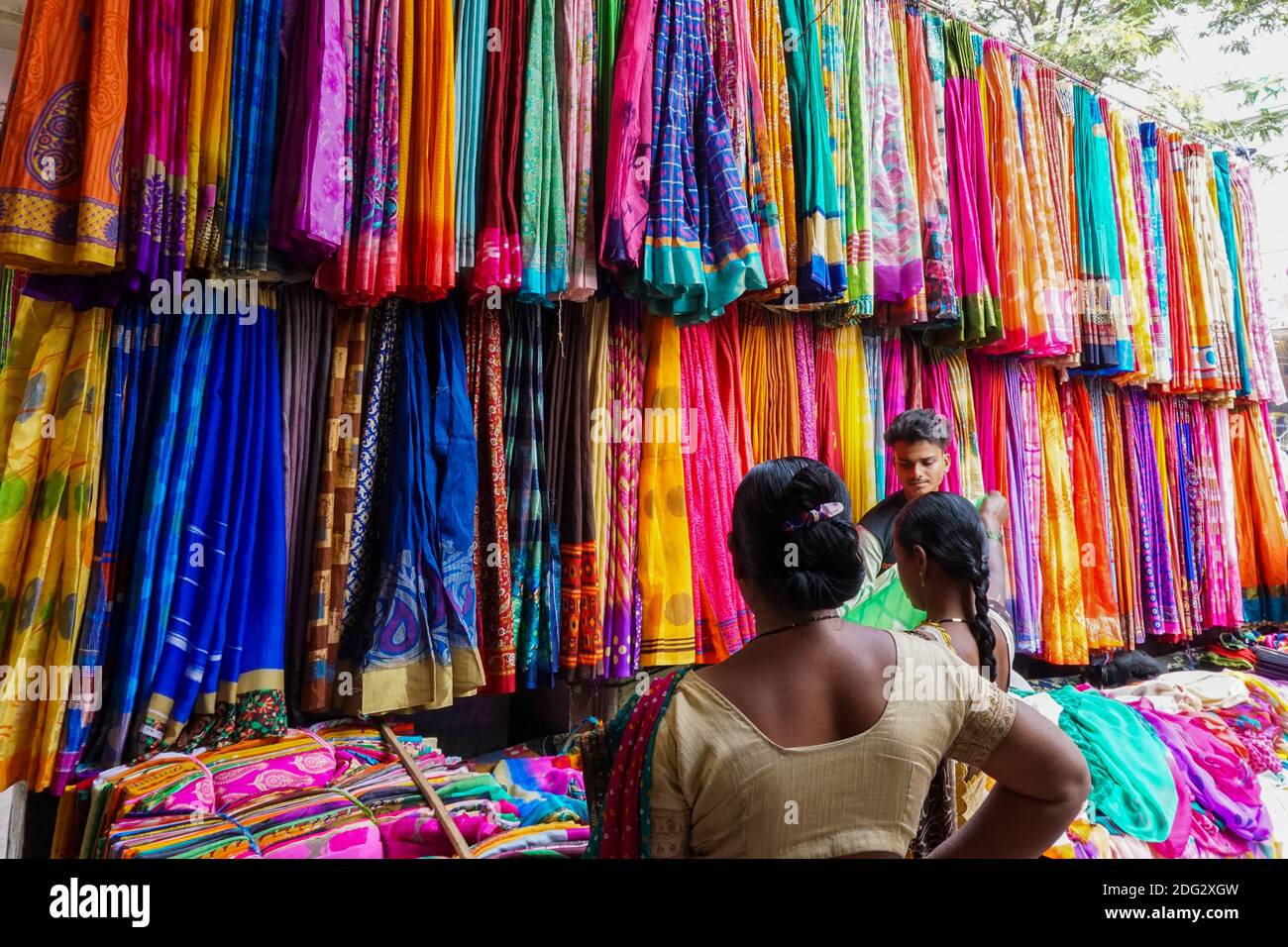 Vendere belle saree colorate sul negozio di strada a Hyderabad, venditore in attesa di clienti, clienti impegnati shopping Foto Stock