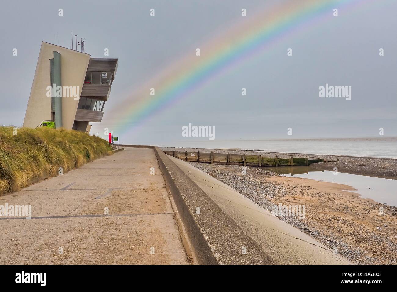 Rainbow at Rossall Beach, Fleetwood, Lancashire, Regno Unito. L'edificio a quattro piani sul lungomare esterno di Rossall Point e' la Torre dell'Orologio costiero di Rossall. Foto Stock