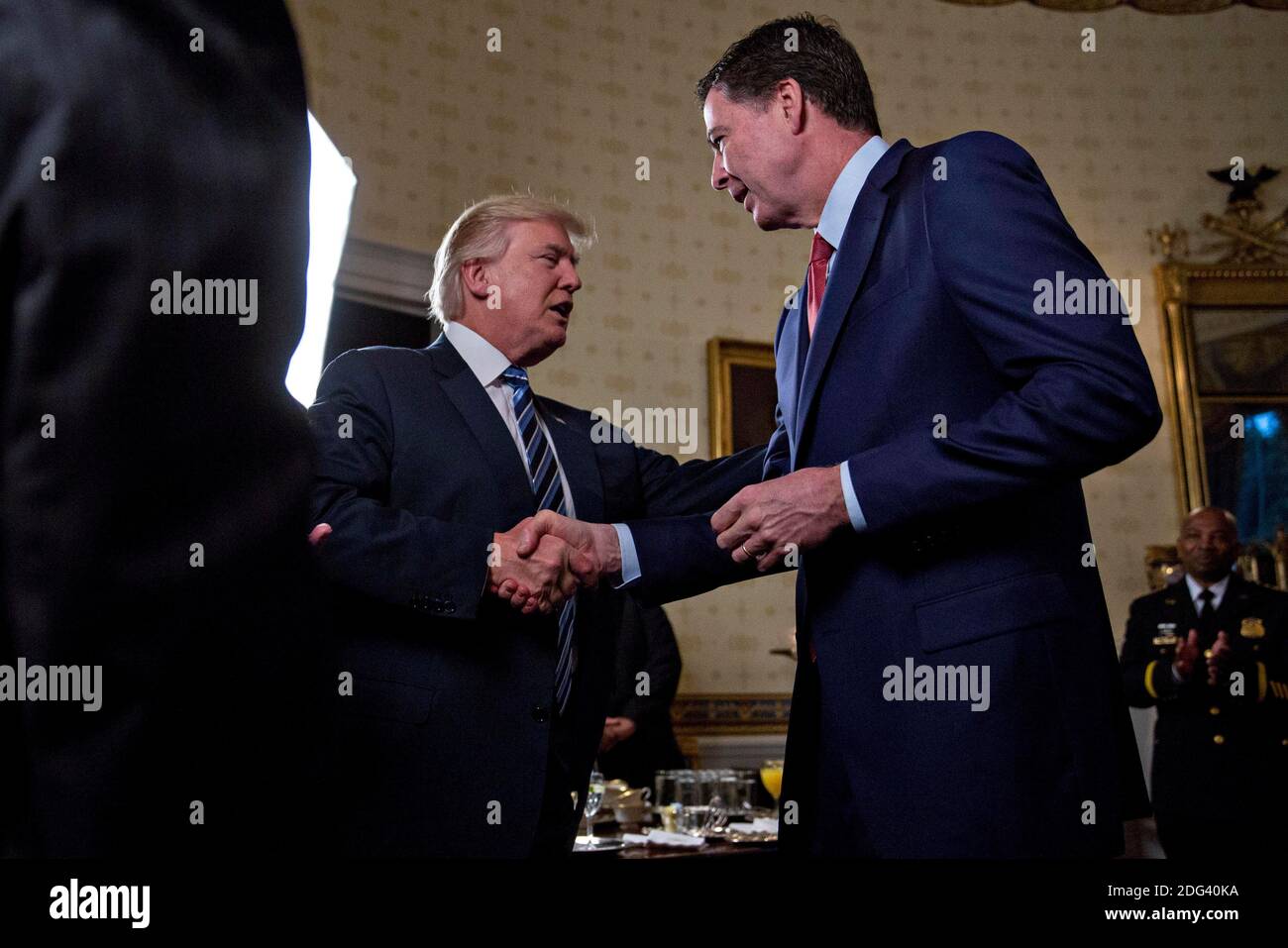 Il presidente degli Stati Uniti Donald Trump, al centro, scuote le mani con James Comey, direttore del Federal Bureau of Investigation (FBI), durante un ricevimento degli ufficiali delle forze dell'ordine e dei primi responsabili nella Blue Room della Casa Bianca a Washington, D.C., Stati Uniti, domenica 22 gennaio 2017. Oggi Trump ha schernito i dimostranti che si sono riuniti per grandi manifestazioni in tutto il mondo e negli Stati Uniti sabato per segnalare il malcontento nei suoi dirigenti, ma in seguito ha offerto un tono più conciliante, affermando che ha riconosciuto tali marce come un "marchio distintivo della nostra democrazia". Fotografo: Andrew Harrer/Bloomberg Foto Stock