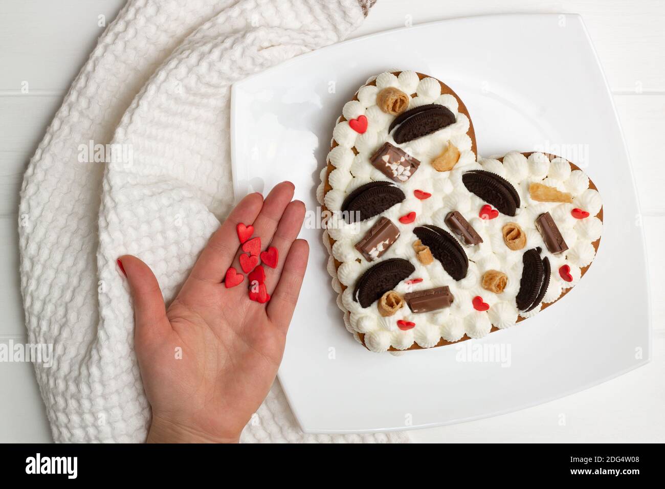 Istruzioni dettagliate per la ricetta della torta a forma di cuore. Passaggio 12: Decorare la torta con gocce di cioccolato, waffle, biscotti. Disposizione piatta. Foto Stock