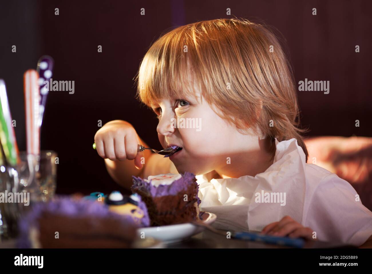 Little Boy di mangiare una torta al cioccolato Foto Stock