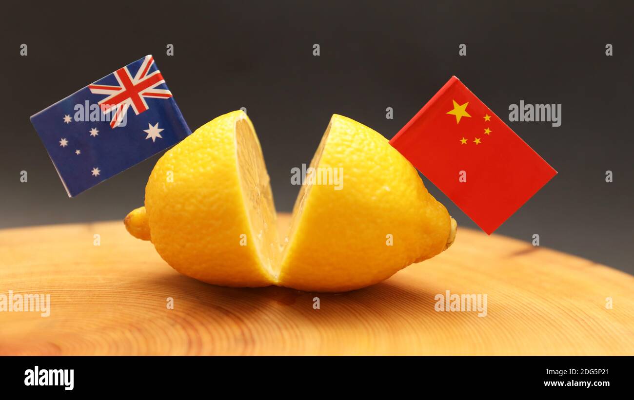 Bandiere australiane e cinesi attaccate in un limone affettato sopra un blocco di triturazione che rappresenta il feudo aspro e amaro teso sulle relazioni internazionali a Foto Stock