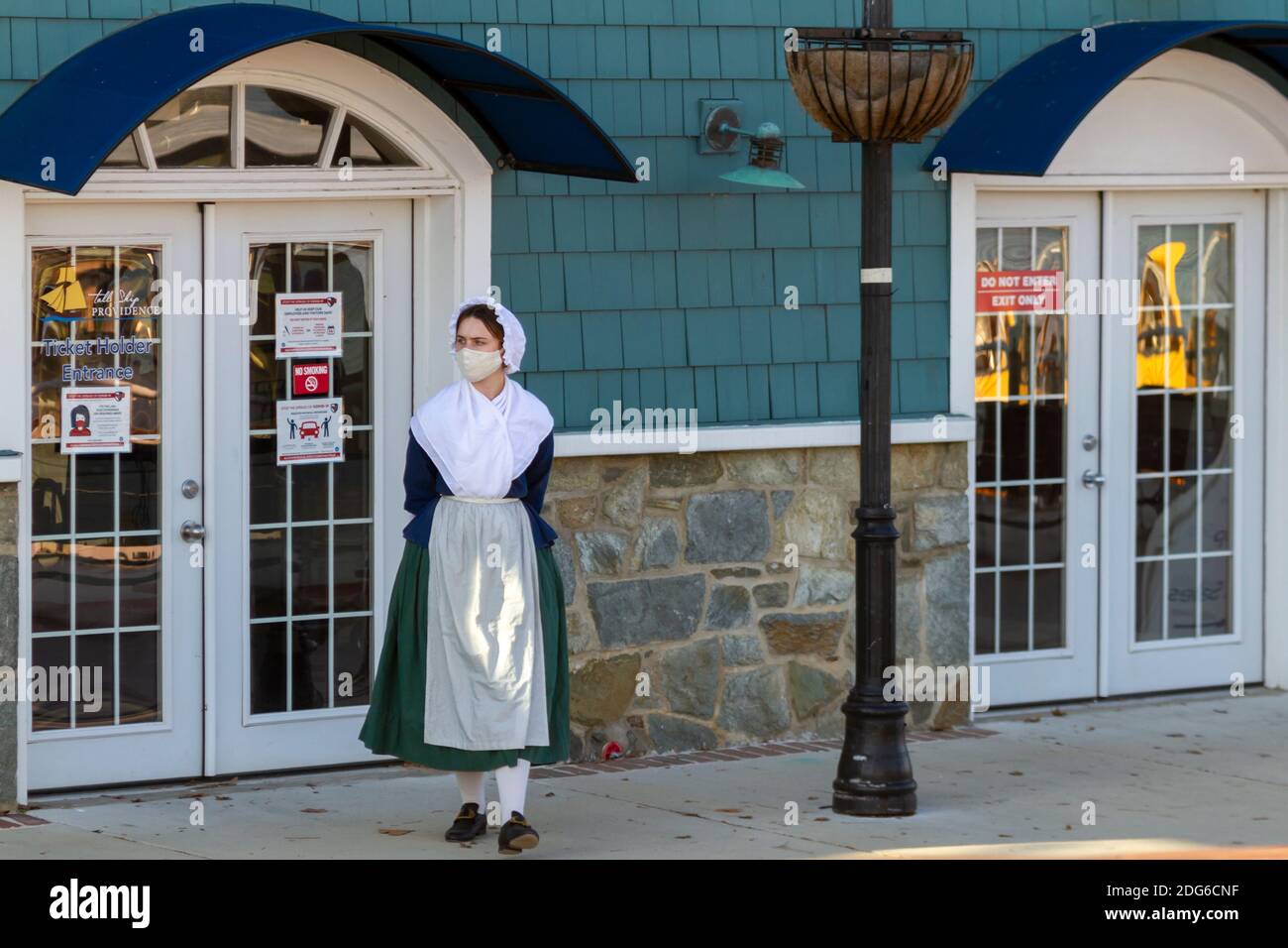 Alexandria, VA, USA 11-28-2020: Una dipendente di ristorante femminile che indossa un costume di vestito donna coloniale e una maschera per il viso a causa di COVID-19 è in attesa al Foto Stock