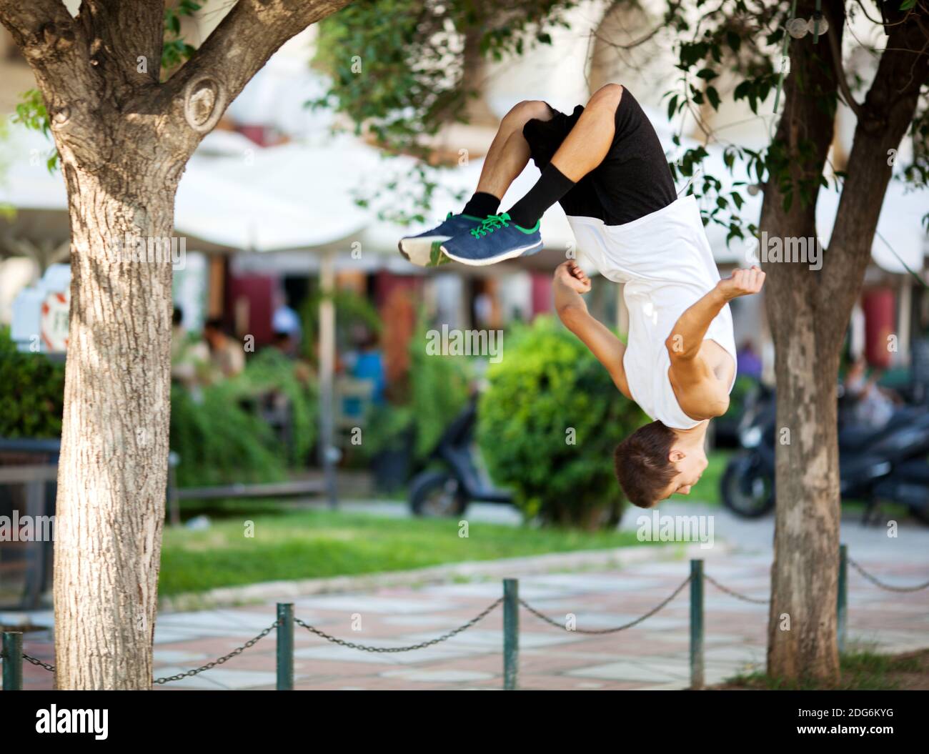 Giovane sportivo che fa il front flip in strada Foto Stock