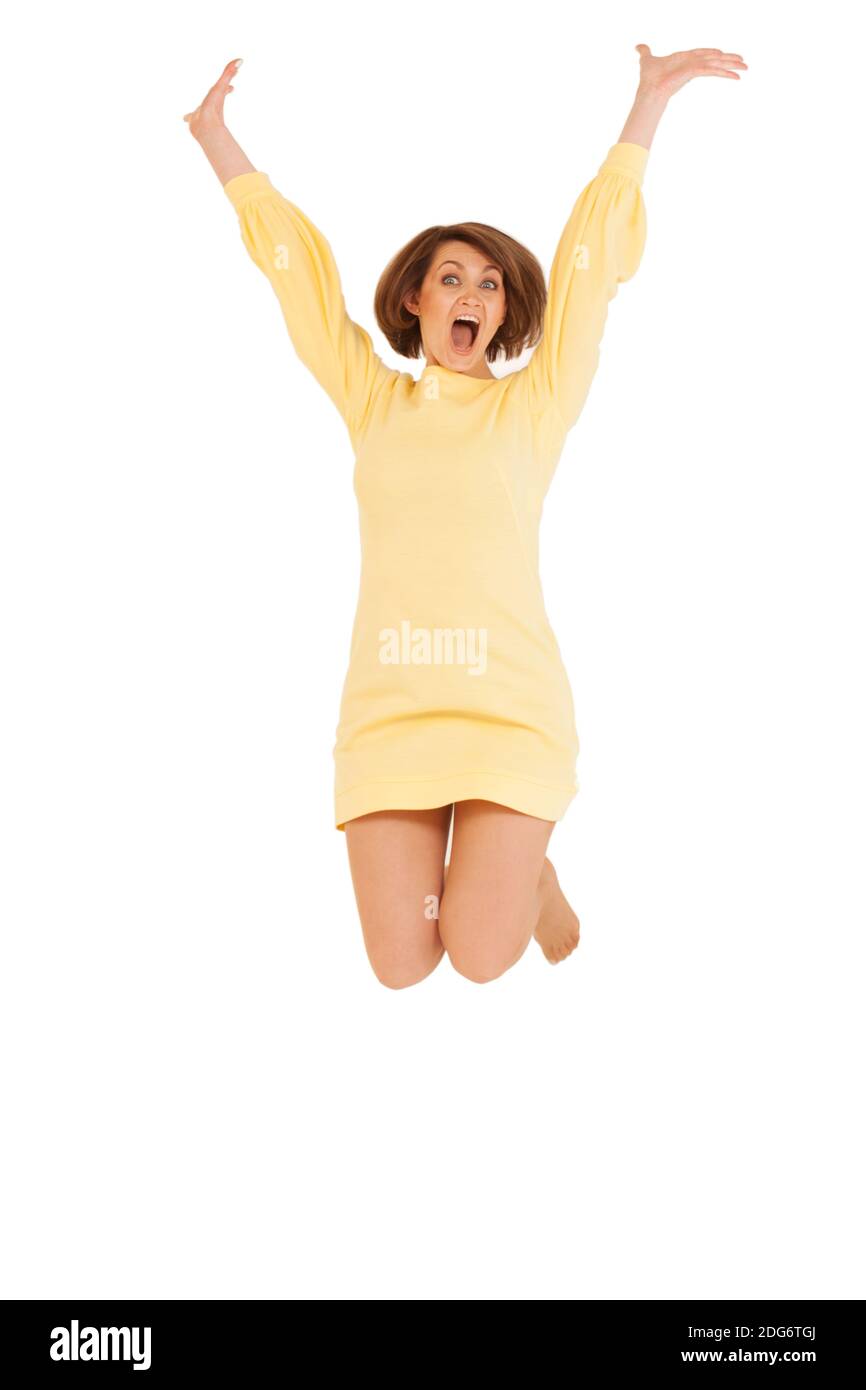 Donna adulta in abito giallo jumping Foto Stock