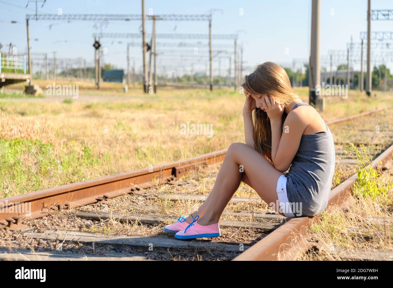 Sconvolto adolescente ragazza seduta sul binario in campagna Foto Stock