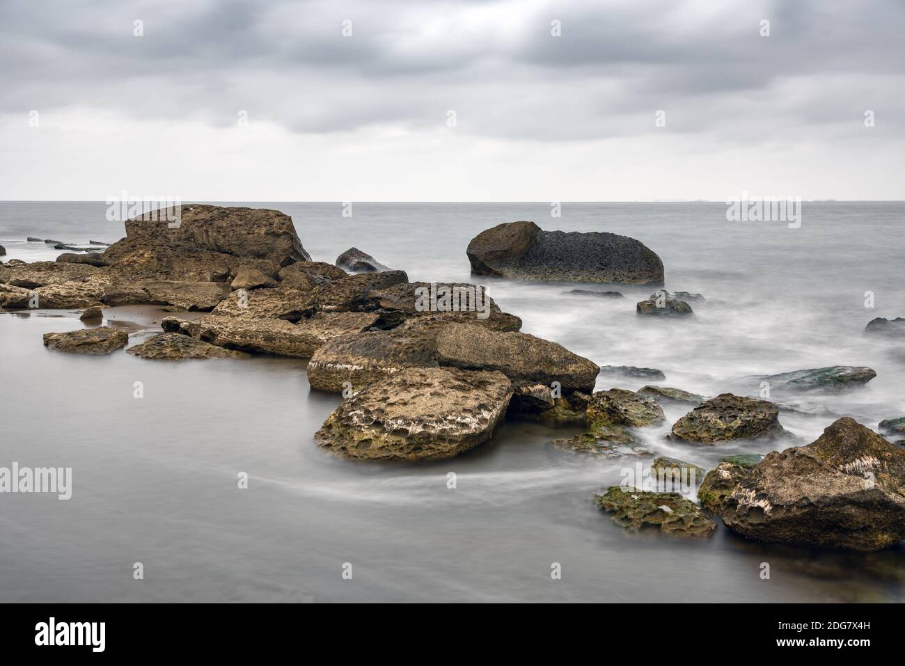Spiaggia rocciosa di mare a tempo nuvoloso, foto a lunga esposizione Foto Stock