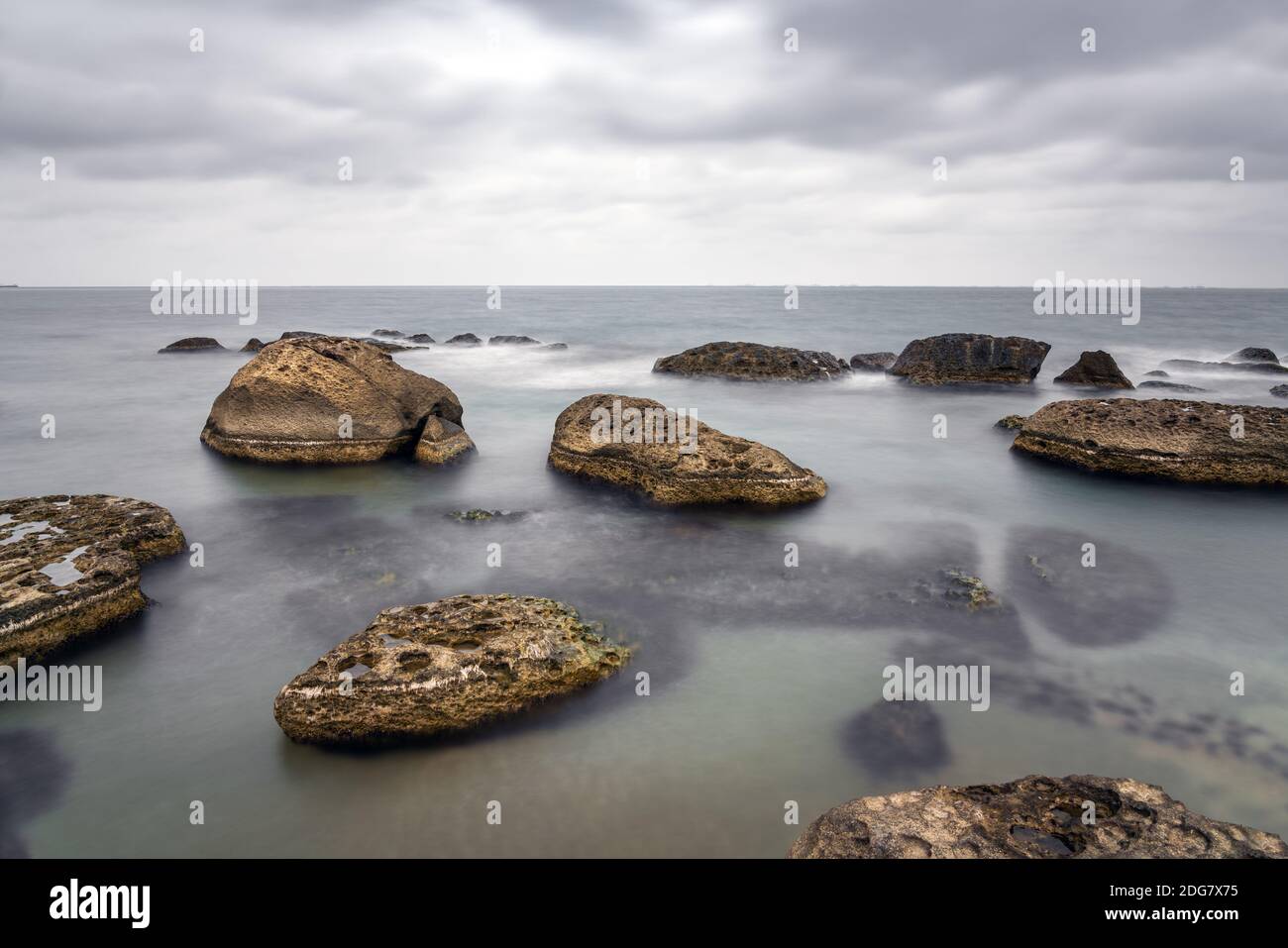 Spiaggia rocciosa di mare a tempo nuvoloso, foto a lunga esposizione Foto Stock