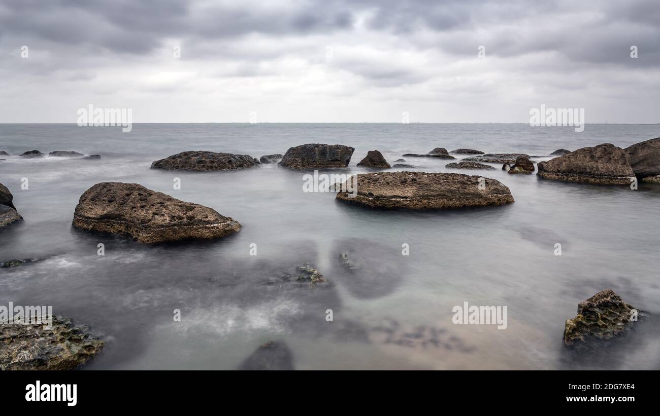 Costa rocciosa del mare a tempo nuvoloso, esposizione lunga acqua sfocata Foto Stock