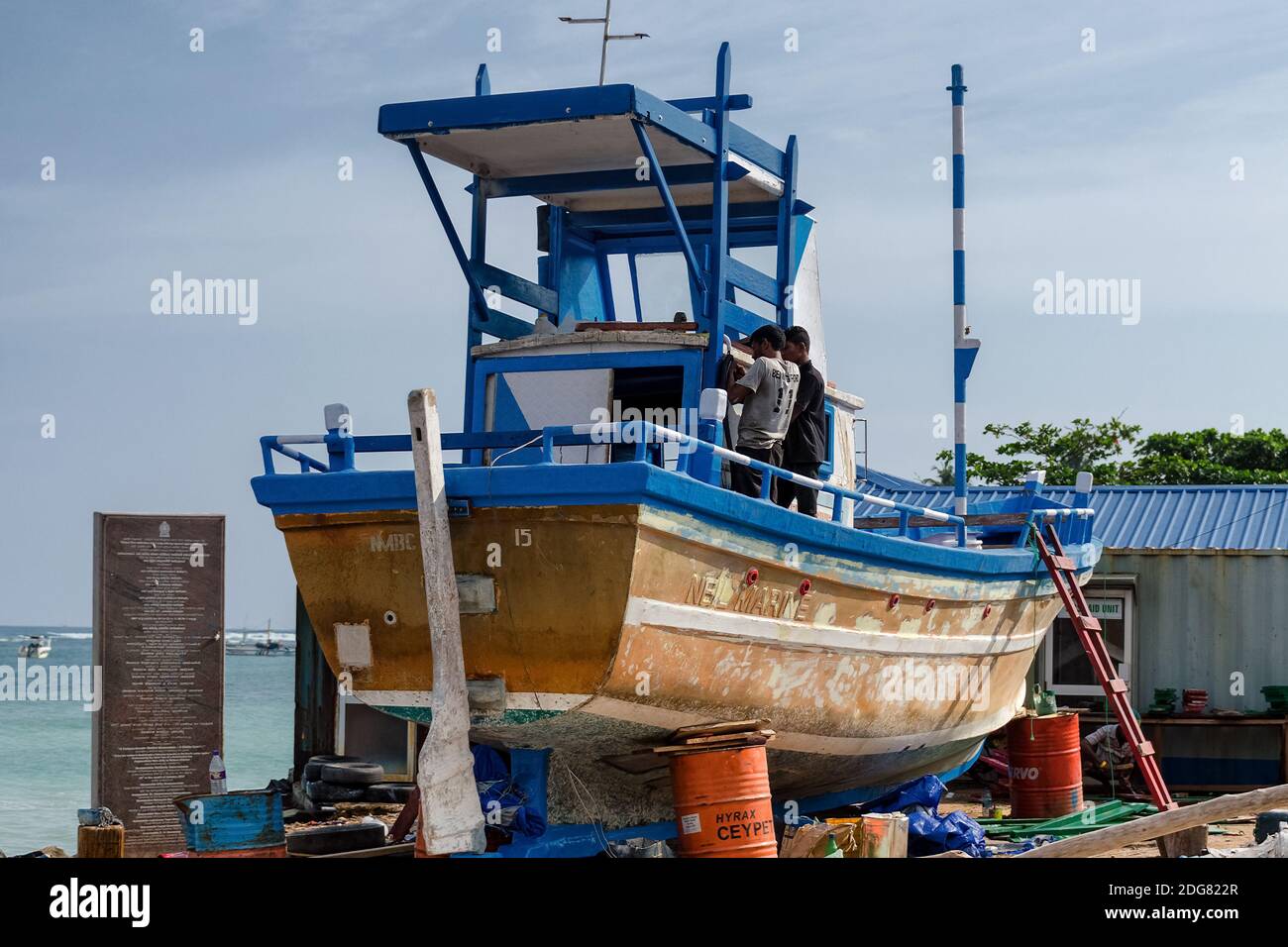Meccanici che riparano una vecchia barca da pesca sulla riva. Sri lanka, Weligama, 2017-12-28 Foto Stock