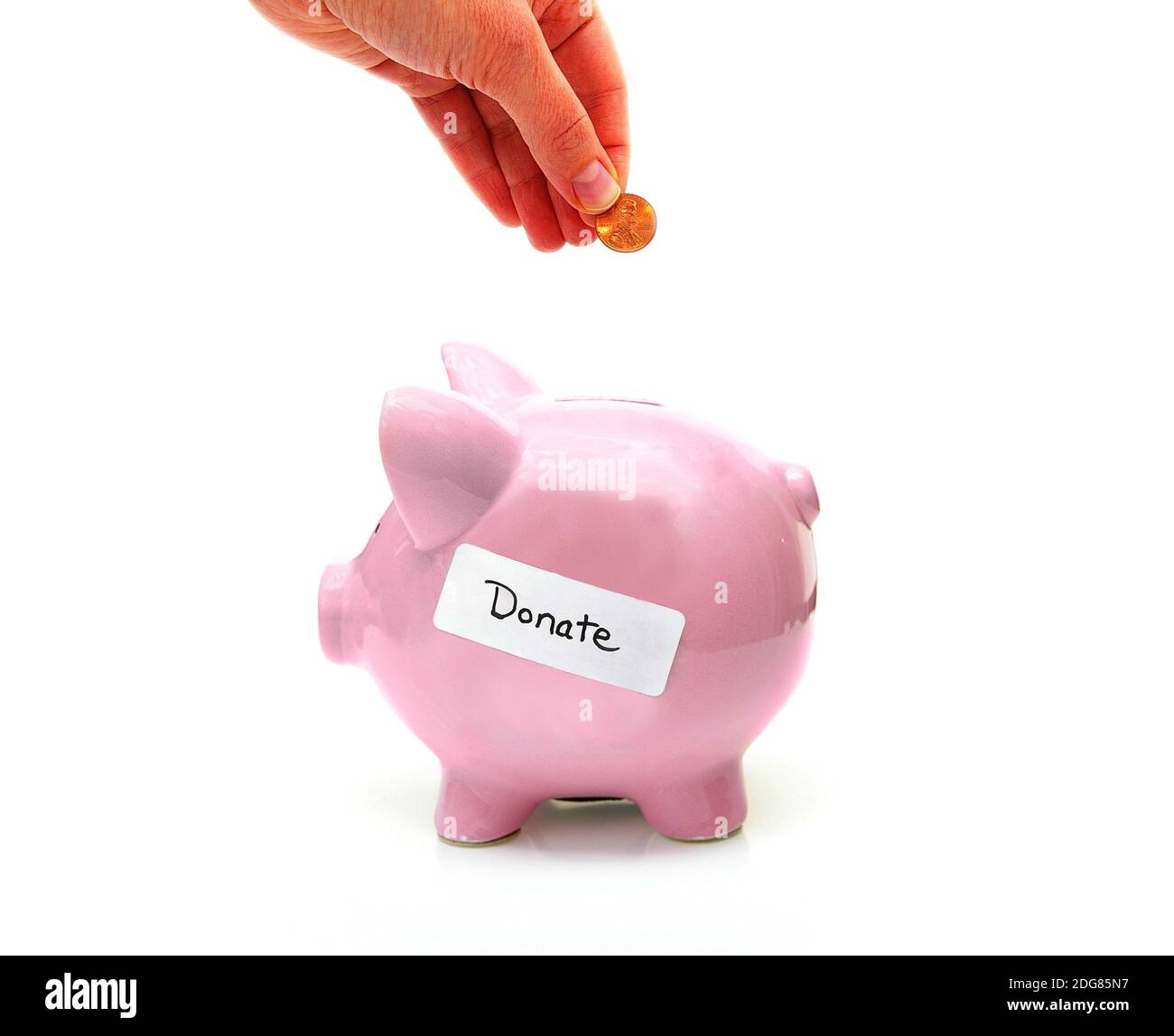 Banca piggy con etichetta donata e mano con penny Foto Stock