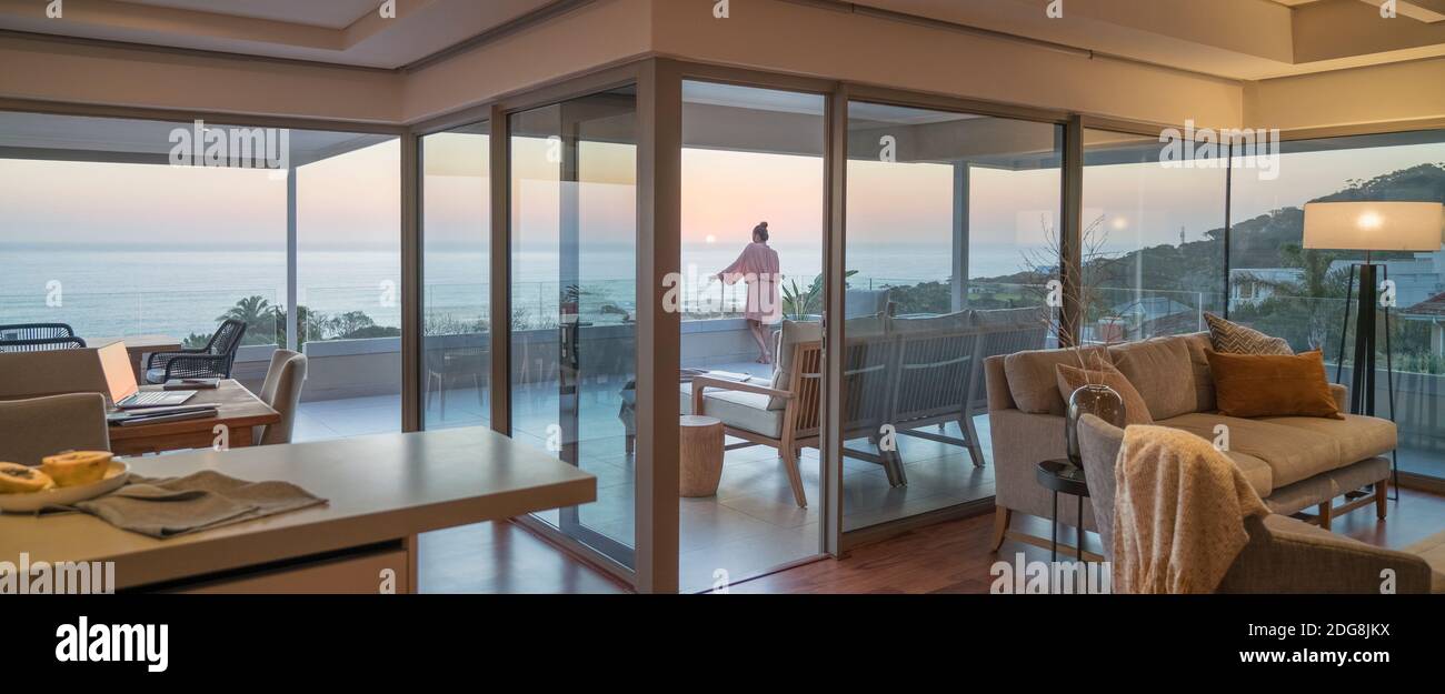 Donna che gode di vista panoramica tramonto oceano su balcone di lusso Foto Stock