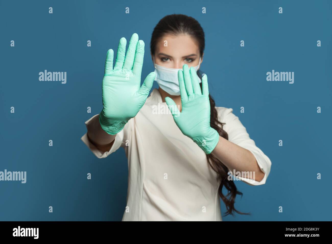 Medicina, sicurezza, vaccinazione e protezione del virus covid-19 concetto. Donna medico mani che mostrano il gesto di arresto su sfondo blu Foto Stock