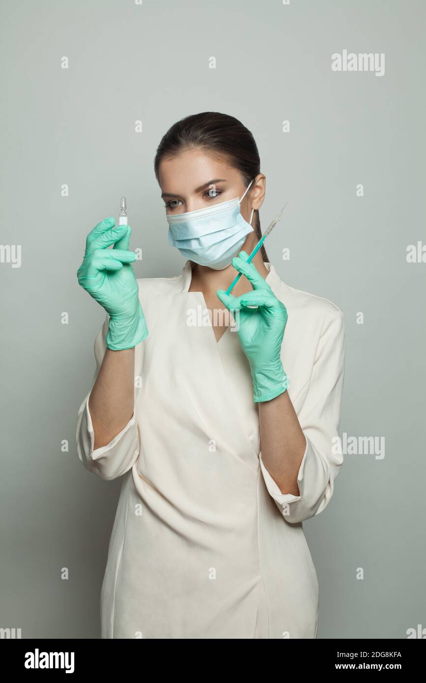 Medico che tiene la siringa e la fiala pronte per l'iniezione su sfondo bianco. Medicina, cosmetologia e concetto di vaccinazione Foto Stock