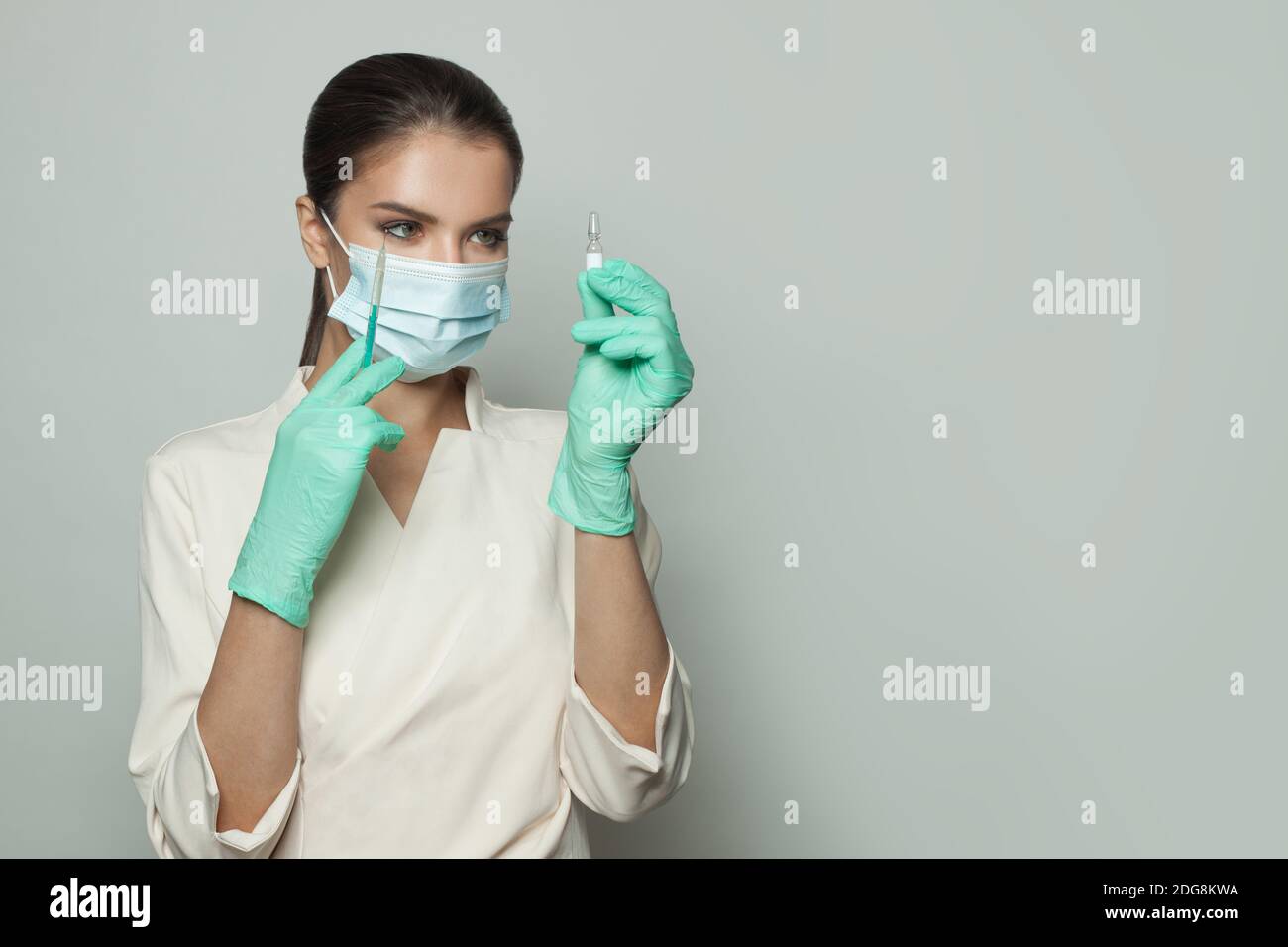 Medico o infermiere con siringa che guarda l'ampolla pronta per l'iniezione su sfondo bianco. Medicina, cosmetologia e concetto di vaccinazione Foto Stock