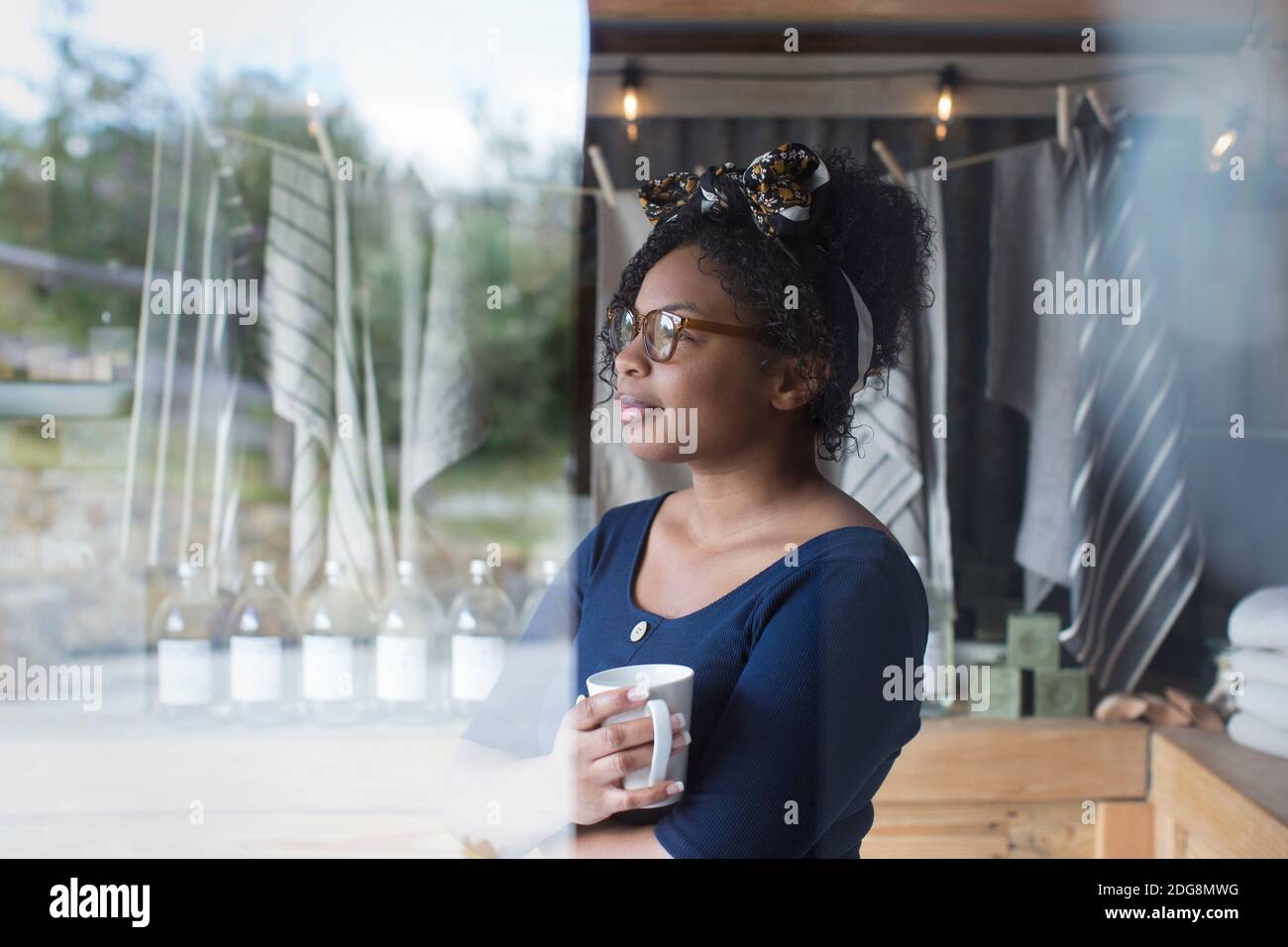 Premuroso proprietario di un negozio femminile che beve caffè alla finestra Foto Stock