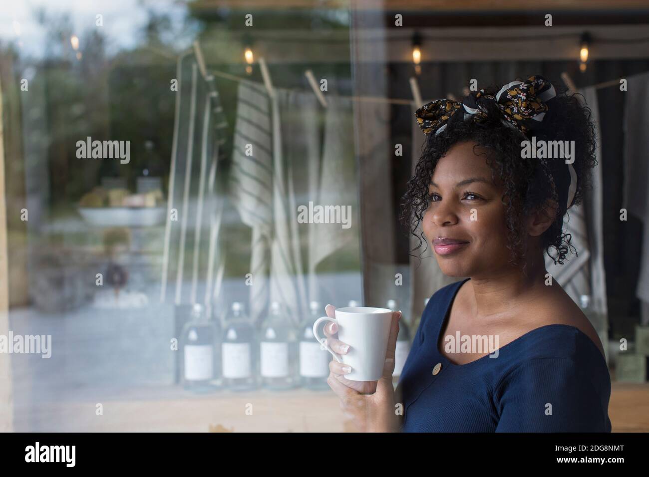 Donna premurosa che beve caffè alla finestra del negozio Foto Stock