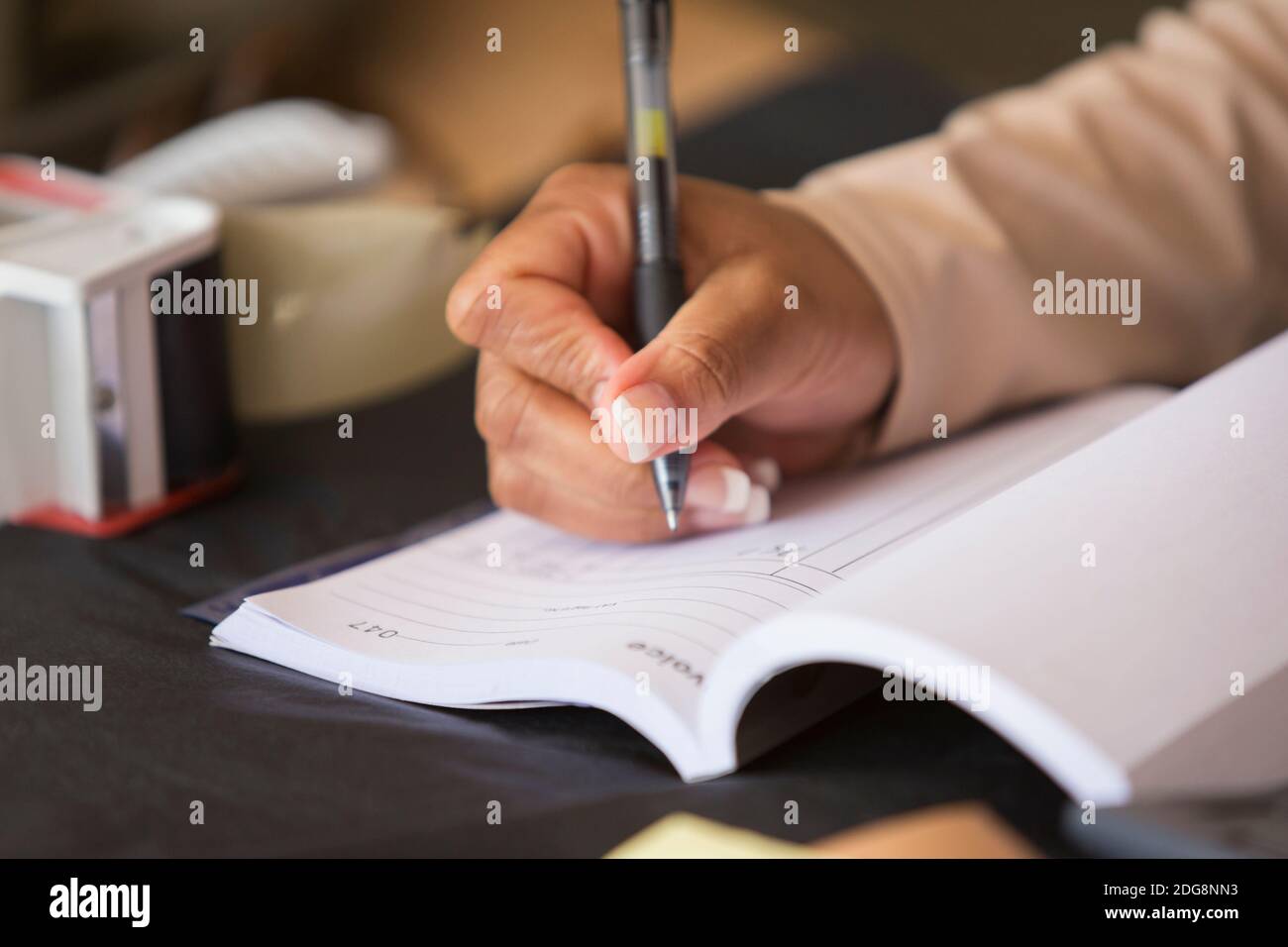 Primo piano il proprietario del negozio femminile che compila la ricevuta ledger Foto Stock
