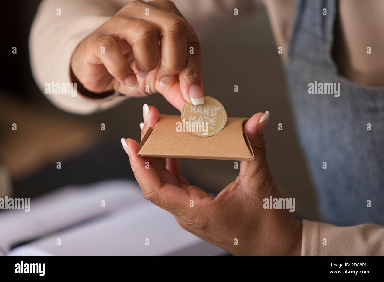 Primo piano il proprietario del negozio femminile che applica l'adesivo fatto a mano alla confezione Foto Stock