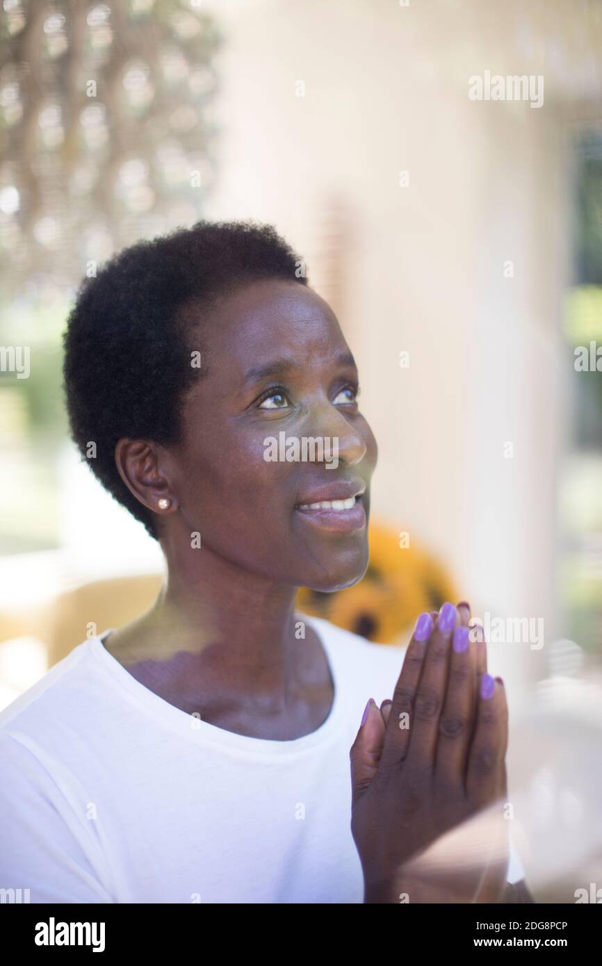 Donna matura che prega con le mani aggrappate Foto Stock