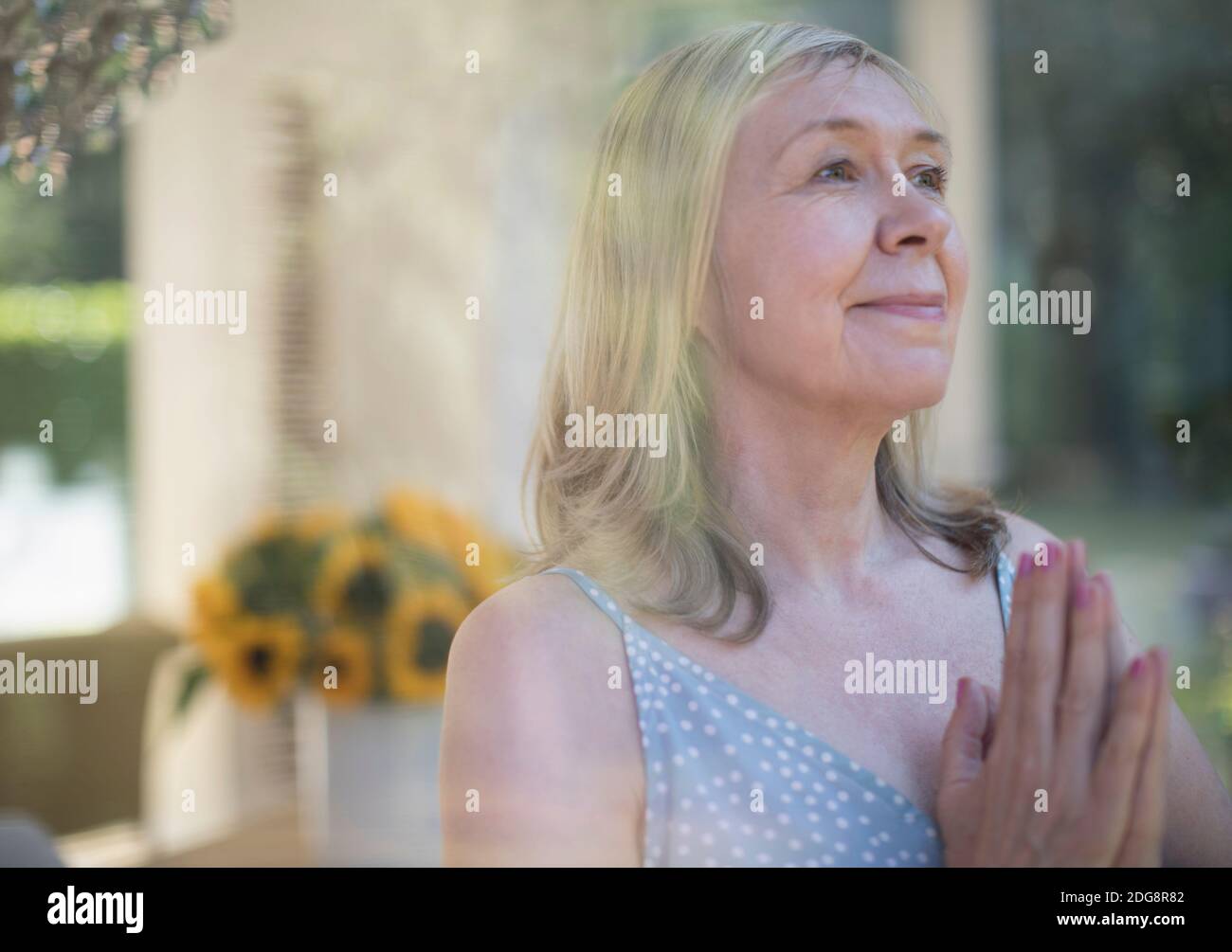 Donna anziana serena meditando con le mani aggrappate Foto Stock