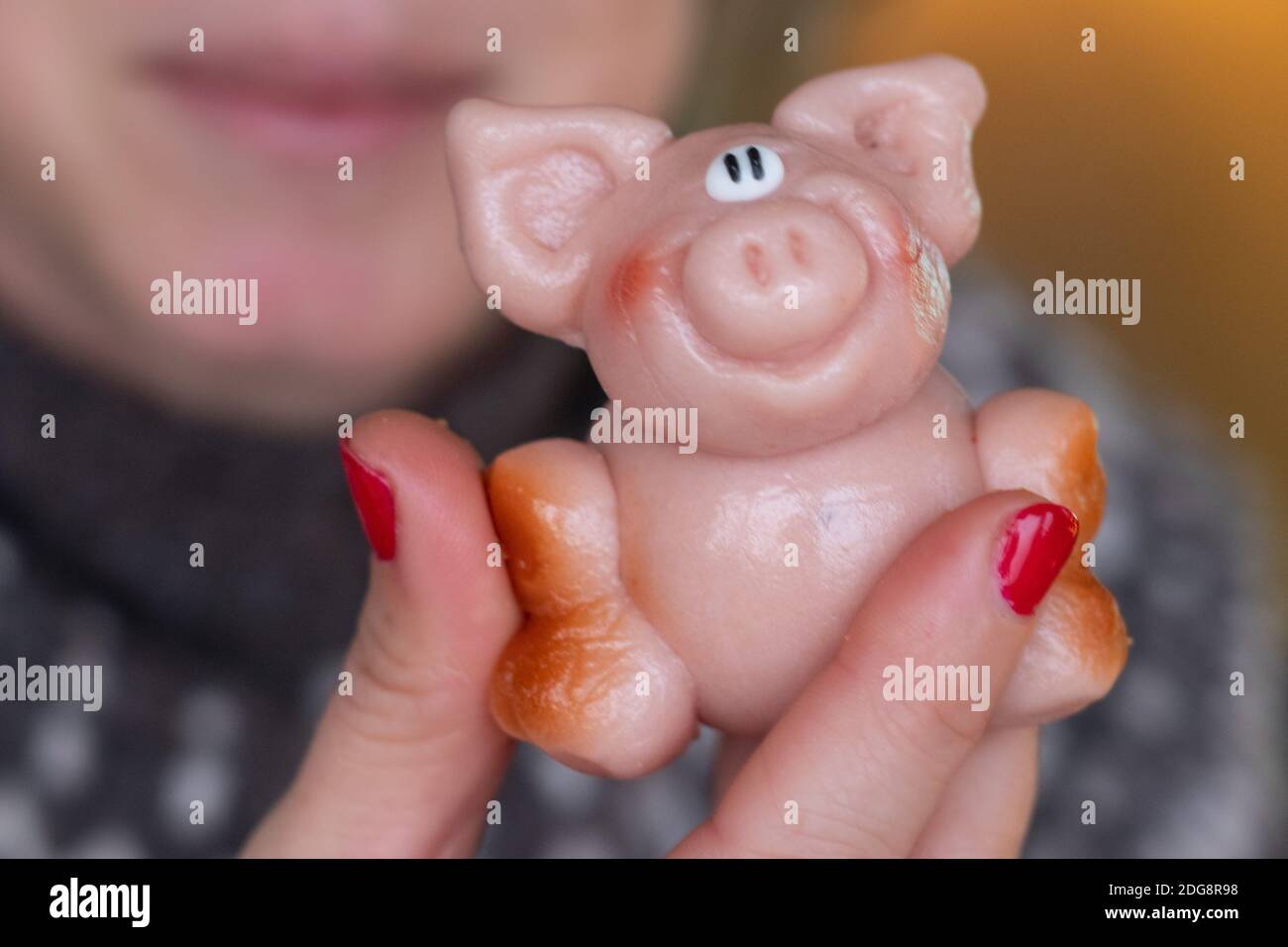 Tenendo un piccolo maiale marzapane rosa per mangiarlo Foto Stock