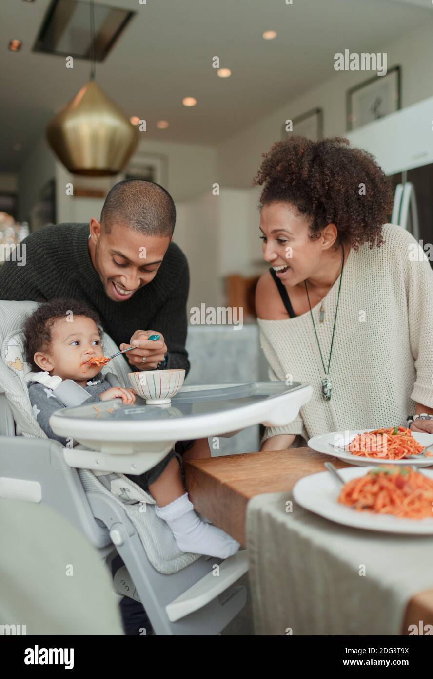 Felice coppia che alimenta la figlia del bambino in seggiolone Foto Stock