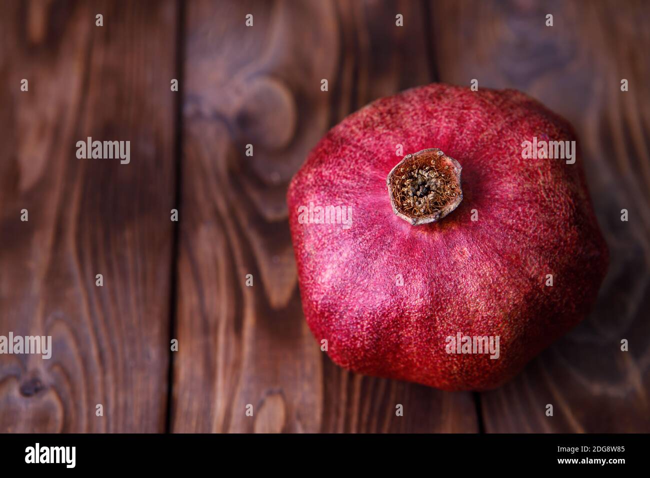 La melograna matura succosa si trova su uno sfondo di legno marrone. Succo di melograno contro il coronavirus. Foto Stock