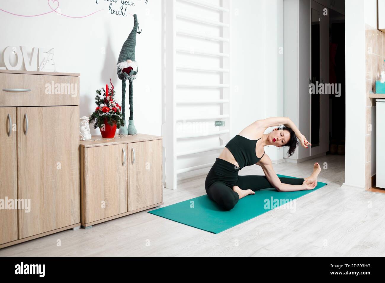 Giovane donna che esercita yoga nel suo proprio appartamento e godendosi il suo giorno Foto Stock